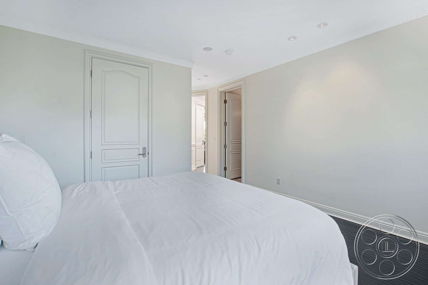 Medit 170 - neutral color palette, recessed ceiling lights, dark hardwood bedroom floors, white painted walls, crown molding details, panel door, close door with decorative trim