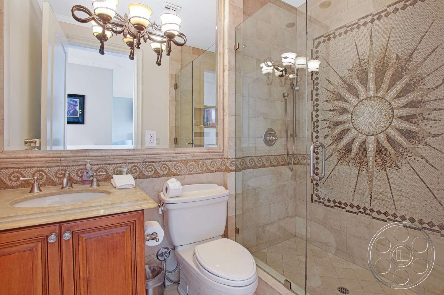 Medit 170 - neutral color palette, wood cabinetry, chandelier lighting, glass shower door, interior bathroom, white painted walls, granite bathroom countertop, toilet with modern design, polished stone shower walls, mosaic tile shower design, framed mirror with silver finish, brushed nickel bathroom fixtures, textured tile bathroom flooring