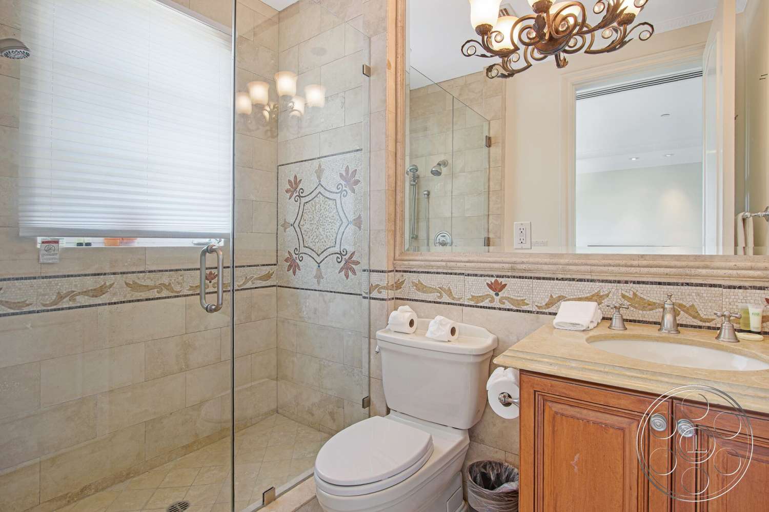 Medit 170 - brushed nickel fixtures, decorative tile backsplash, traditional chandelier, interior bathroom, natural stone shower walls, tiled shower floor, textured stone accent wall, custom wood vanity, glass-enclosed shower, marble sink countertop, white plantation shutter windows