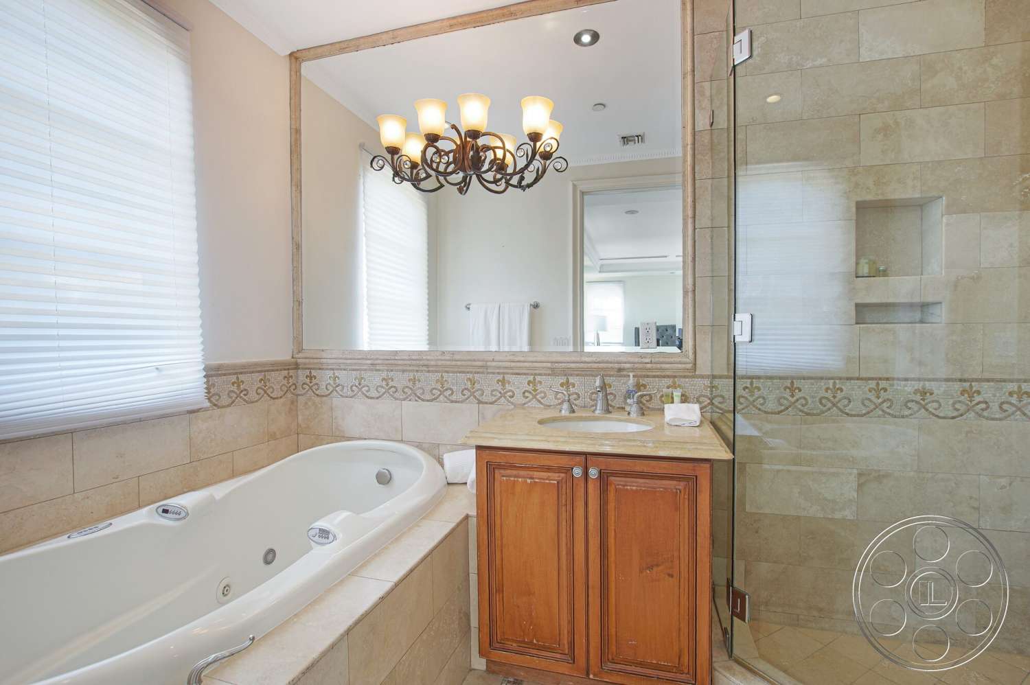 Medit 170 - glass shower enclosure, decorative tile border, recessed ceiling lighting, white freestanding soaking tub, crystal chandelier lighting, ceramic tile bathroom walls, natural stone tile flooring, wood vanity with decorative paneling, large mirror with decorative frame