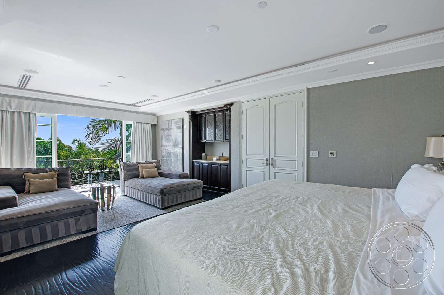 Medit 170 - dark wood cabinetry, dark hardwood flooring, king-sized bed, textured wall treatment, plush area rug, fabric curtains, crown molding details, tropical garden view, large glass window for natural light, luxurious bedroom interior, upholstered chaise lounge, bay windows with balcony access