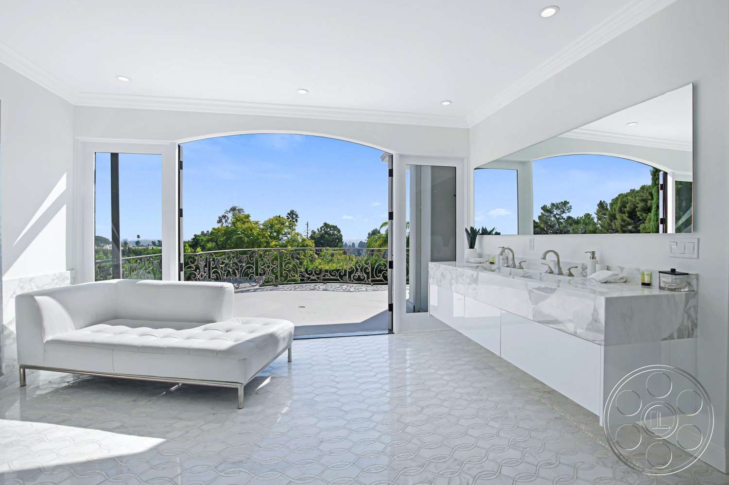 Medit 170 - rectangular mirror, floor-to-ceiling windows, arched doorways, decorative wrought iron railing, white painted walls, marble bathroom flooring, exterior balcony view, modern double sink vanity with marble countertop, plush white chaise lounge