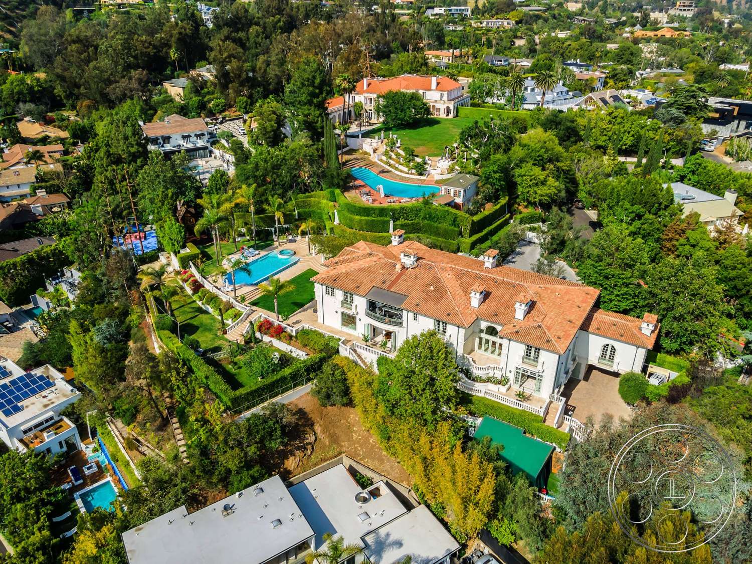 Medit 171 - exterior, landscaped garden, white stucco walls, lush greenery, outdoor seating area, rectangular swimming pool, poolside lounge area, surrounding tree canopy, sunny hillside location, terra cotta tile roof, paver stone pathways, hedge privacy walls, Mediterranean villa, multiple outdoor terraces, broad stairs leading to entrance