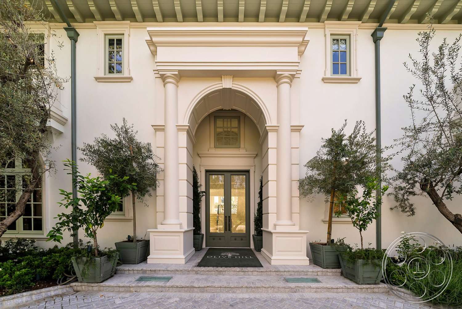Medit 171 - exterior, green window frames, decorative ceiling beams, landscaped garden area, stucco wall finish, stone paver walkway, arched entranceway, intricate door hardware, columned portico, olive trees in planters, elegant front door