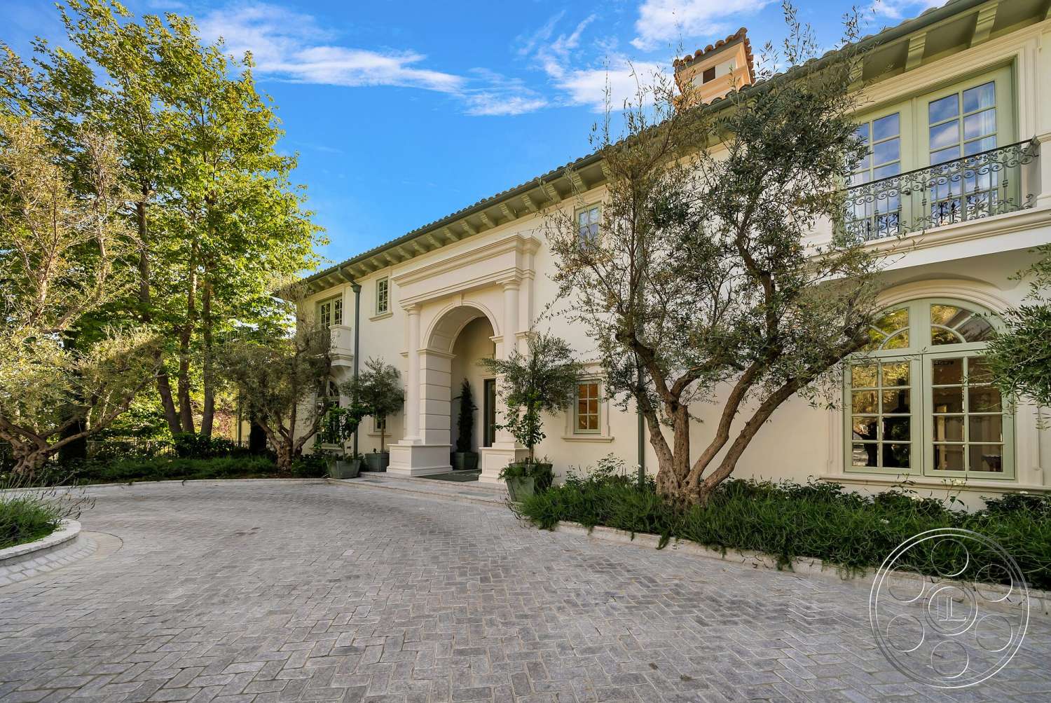 Medit 171 - exterior, paver driveway, landscaped gardens, mature trees, concrete steps, brick walkway, gabled roof, curved driveway, white stucco exterior, arched entrance, iron balcony railing, green window frames, dormer windows, colonial architectural style, garden edging