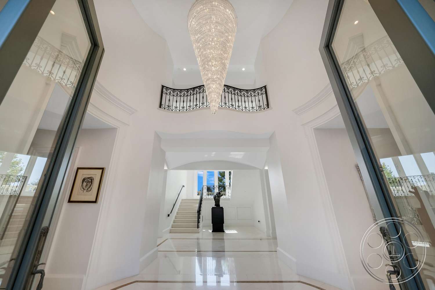 Medit 171 - high ceilings, polished marble flooring, arched doorways, modern chandelier, built-in lighting, curved staircase, white painted walls, wrought iron balcony railing, open foyer space