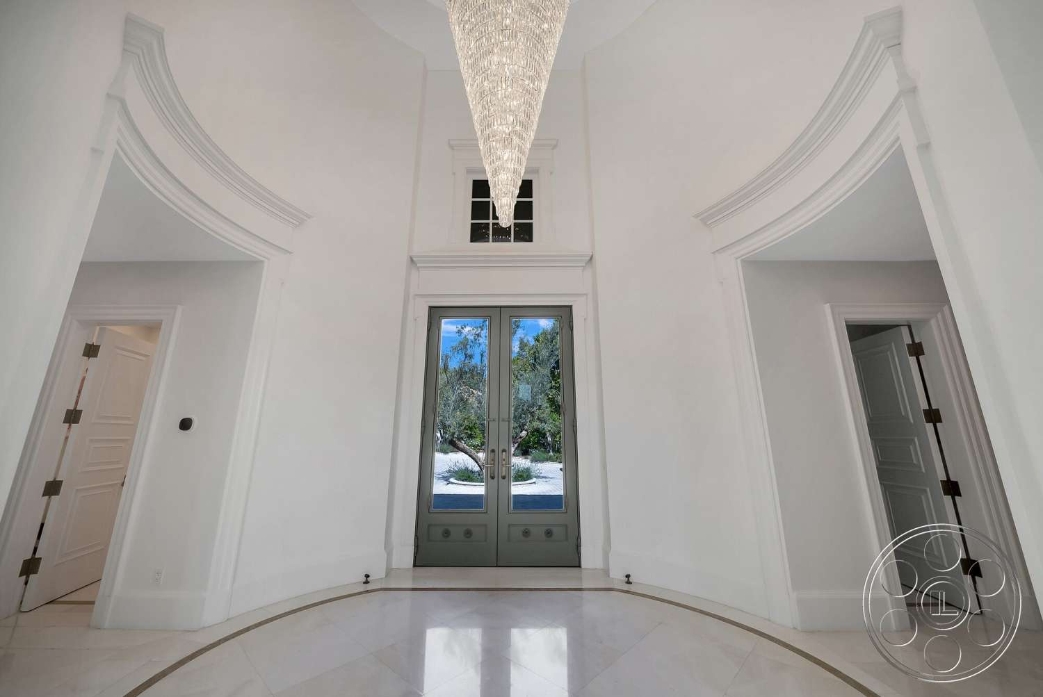 Medit 171 - floor-to-ceiling windows, arched doorways, intricate moldings, double front doors, chandelier light fixture, smooth wall surfaces, white painted walls, symmetrical design elements, marble entryway flooring, circular foyer shape