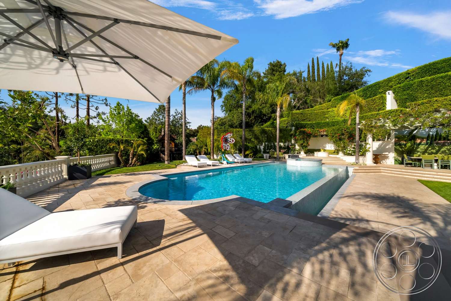 Medit 171 - exterior, landscaped garden, green hedges, tall palm trees, white lounge chairs, balustrade, rectangular pool, sunny outdoor setting, stone patio flooring, concrete pool border, large umbrella shade, modern outdoor living space, terracotta outdoor dining area
