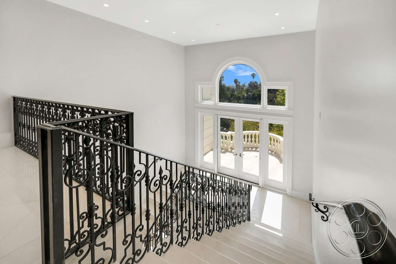 Medit 171 - natural light, floor-to-ceiling windows, arched window, spacious foyer, black wrought iron railing, white painted walls, open balcony view, marble staircase flooring, elegant stairwell design