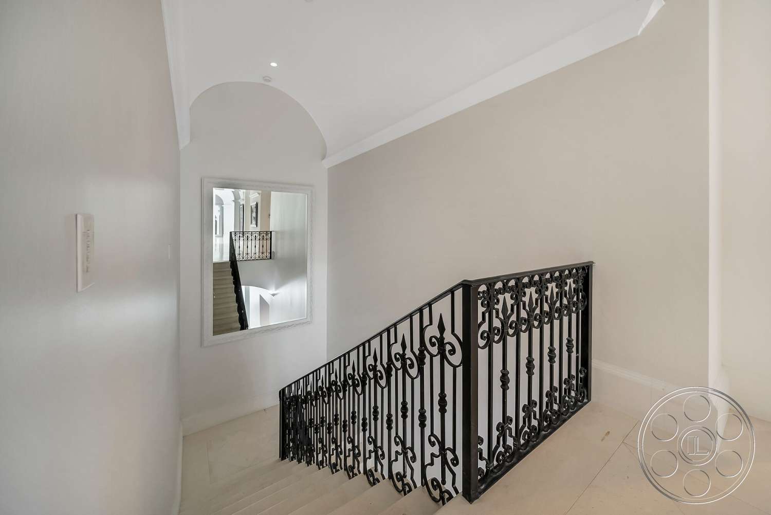 Medit 171 - neutral color palette, arched ceiling, black wrought iron railing, smooth painted walls, minimalist architectural style, interior staircase, open stairwell design, large decorative mirror, light-colored marble flooring, natural light from upper floors