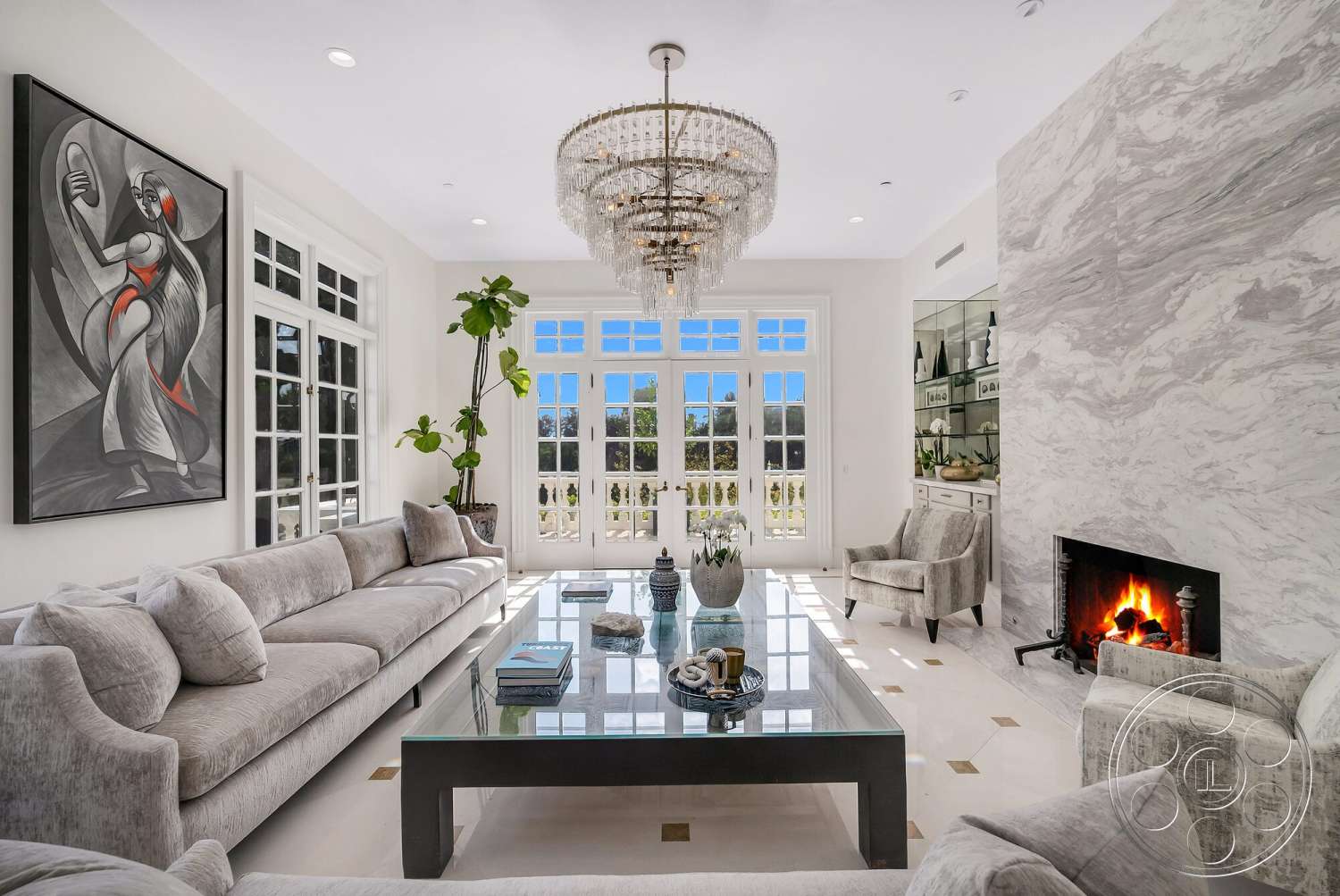 Medit 171 - natural light, stone fireplace, open floor plan, abstract wall art, glass coffee table, crystal chandelier, large floor-to-ceiling windows, marble feature wall, green indoor plant, glossy tile flooring, white painted walls, modern sectional sofa, built-in shelving unit, gray upholstered accent chairs