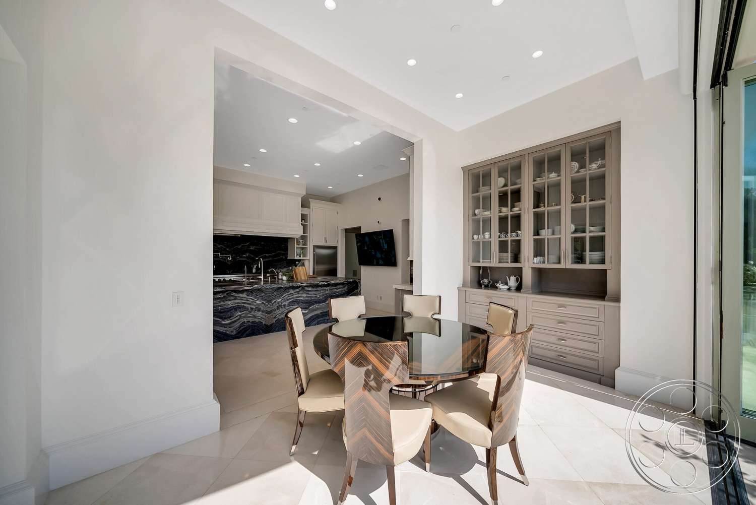 Medit 171 - open concept layout, glass dining table, light-colored tile flooring, stainless steel kitchen appliances, recessed lighting fixtures, polished marble countertop, interior kitchen with contemporary design, wood dining chairs with geometric pattern, high-gloss white kitchen cabinetry, textured backsplash with stone accents
