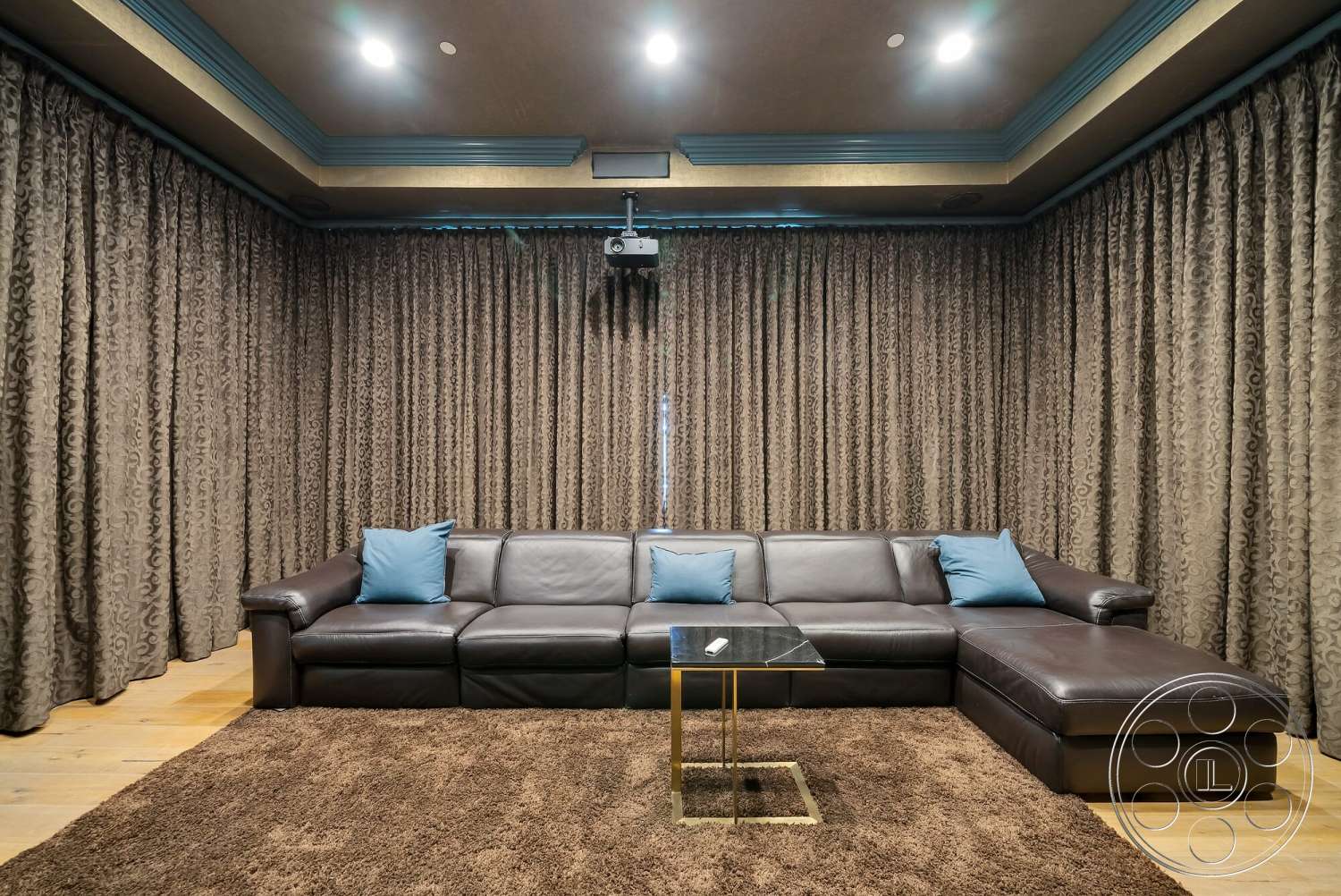 Medit 171 - dark wood flooring, decorative throw pillows, plush area rug, recessed ceiling lights, leather sectional sofa, modern glass coffee table, projector mounted on ceiling, floor-to-ceiling fabric curtains, textured drapery, blue accent ceiling trim, cozy movie room setting