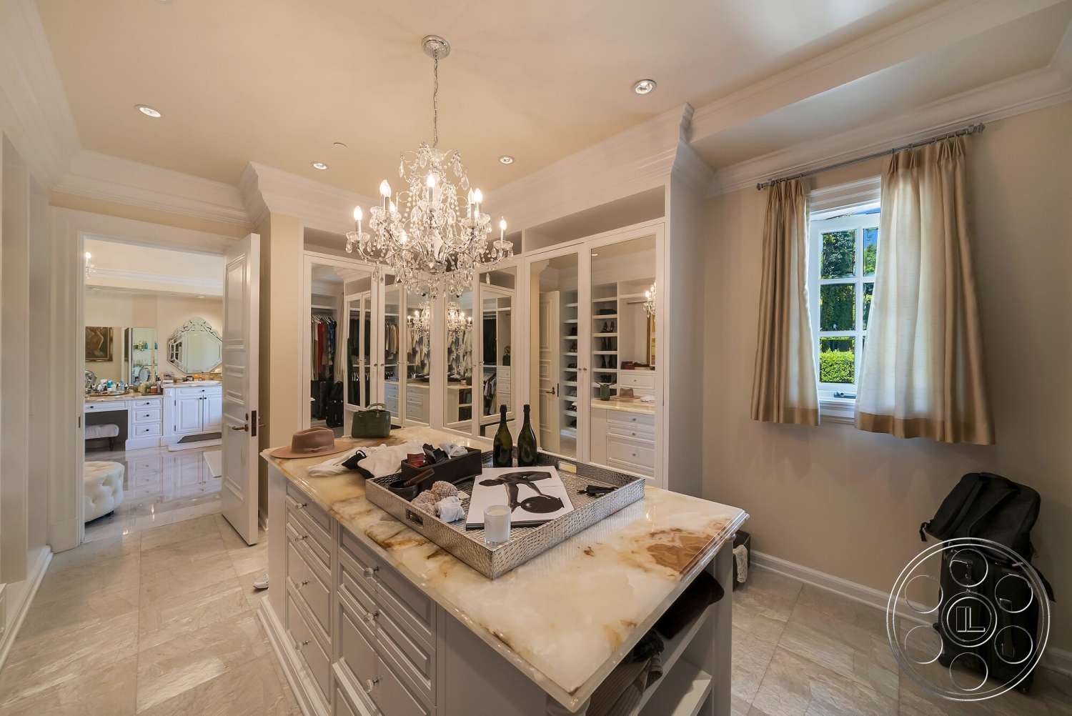 Medit 171 - white cabinetry, chandelier lighting, decorative crown molding, marble flooring, polished stone surface, open layout design, cream painted walls, glass mirror closet doors, luxury dressing room, window with soft drapes, dressing table with marble top, elegant closet space