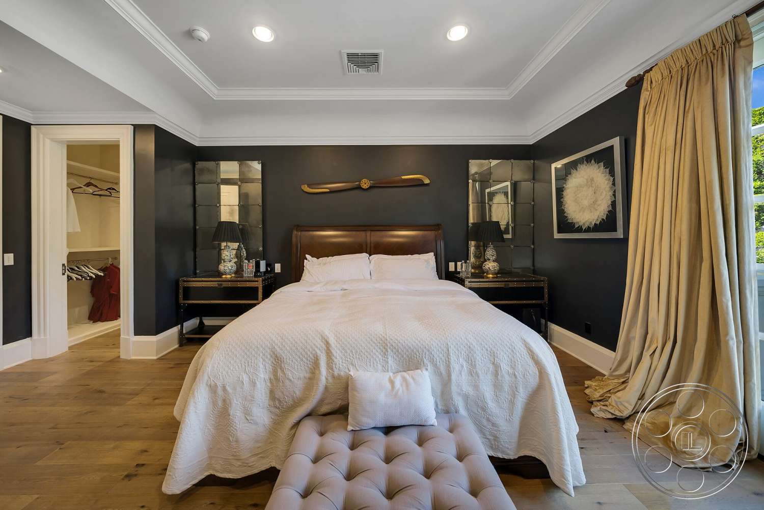 Medit 171 - cozy seating area, floor-to-ceiling curtains, textured wall treatment, upholstered headboard, decorative table lamps, dark accent walls, hardwood bedroom floors, mirror accent wall, white crown molding details, walk-in closet entry