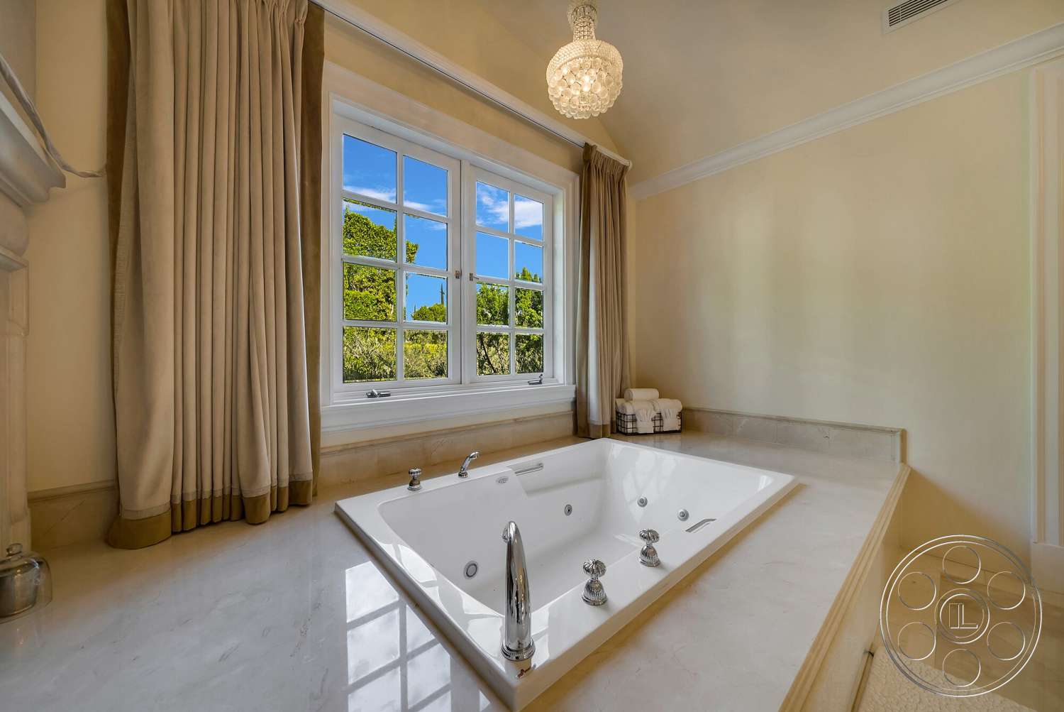 Medit 171 - stone flooring, textured plaster walls, luxury bathroom interior, glass window panels, marble bathtub surround, hanging crystal chandelier, beige fabric drapes