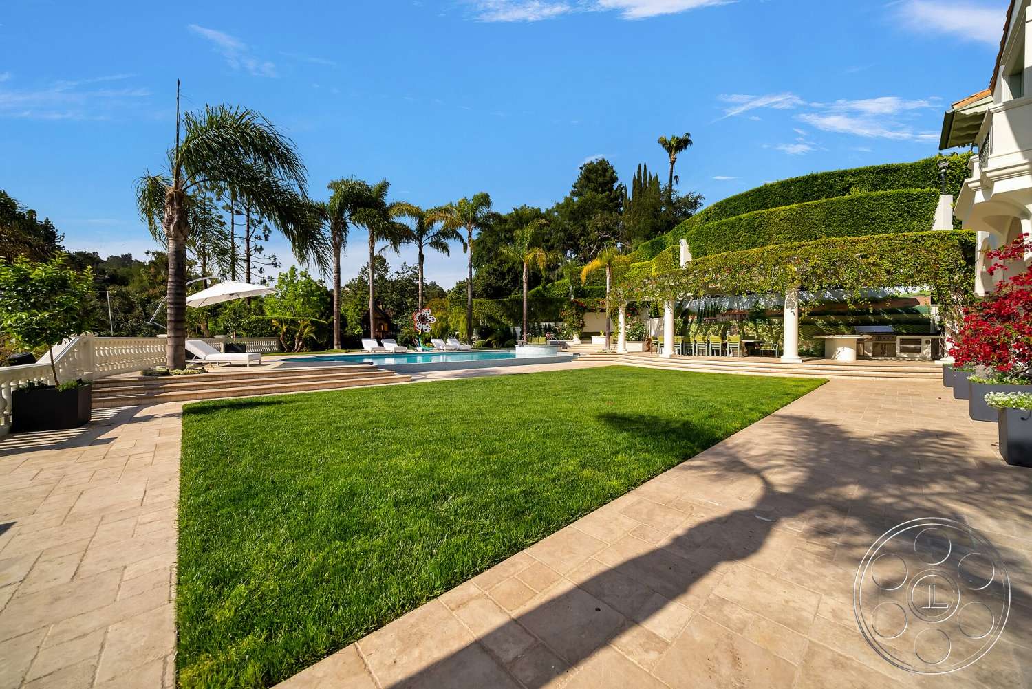 Medit 171 - exterior, fenced garden area, rectangular swimming pool, lush green lawn, stone patio flooring, palm trees landscaping, surrounding hillside view, tropical garden setting, outdoor lounge area with sun loungers, white concrete pool border, decorative pergola structure, veranda with columns, stepped terrace design