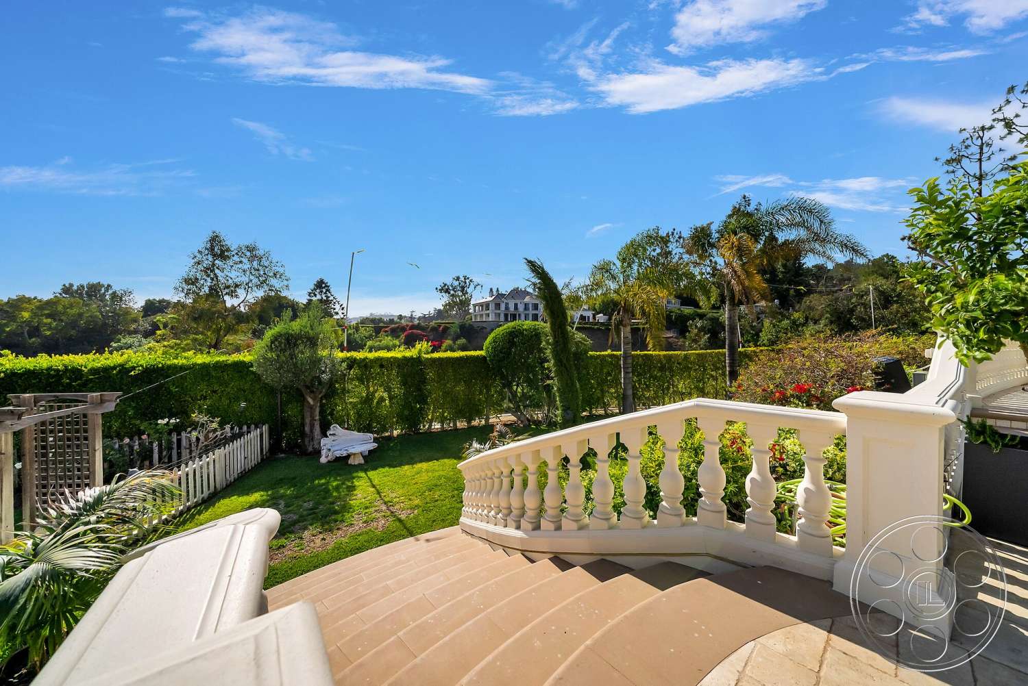 Medit 171 - exterior, tropical plants, patio area, landscaped yard, green hedges, blue sky, paved stone patio, manicured garden, curved staircase, white balustrade railing, stone staircase steps, surburban setting, multi-story home in background