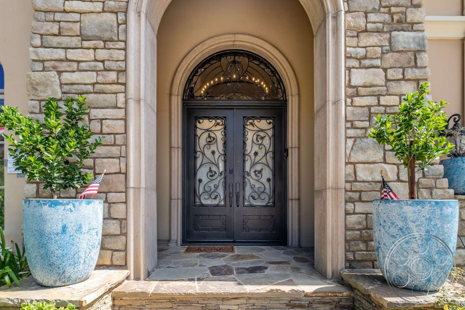 Medit 172 - exterior, slate stone flooring, arched entrance, natural stone steps, stone facade walls, decorative wrought iron door, large blue ceramic planters, green shrubbery with small flags, soft earth tone walls