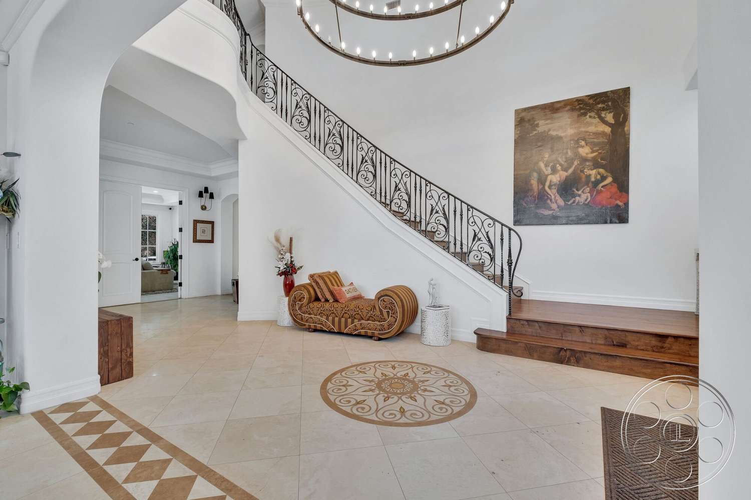 Medit 172 - arched doorways, modern interior design, coffered ceiling details, interior entrance hall, chandelier lighting fixture, wood accent bench, tile flooring with decorative inlay pattern, curved wrought iron staircase railing, light wood staircase steps, decorative accent wall with framed artwork