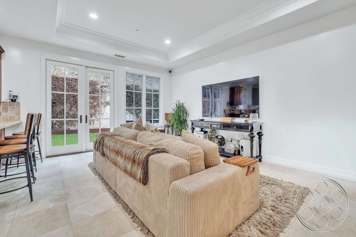Medit 172 - tile flooring, recessed lighting, textured area rug, open floor plan, french doors, white painted walls, crown molding details, built-in entertainment cabinet, bar counter with stools, neutral colored sectional sofa, soft fabric throw blanket