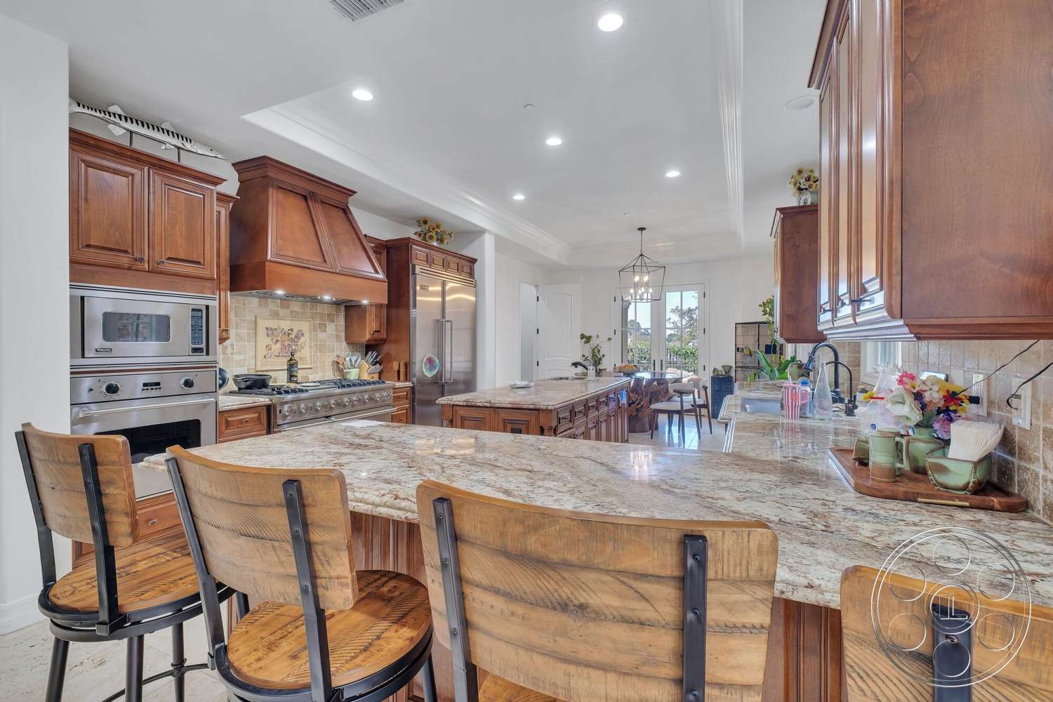 Medit 172 - dark wood cabinetry, natural light, stainless steel appliances, floor-to-ceiling windows, view of outdoor space, pantry door, recessed ceiling lighting, granite kitchen countertops, crown molding details, open concept kitchen layout, kitchen island with seating, marble tile backsplash, exposed wood bar stools, centrepiece pendant lighting, tiled kitchen floors
