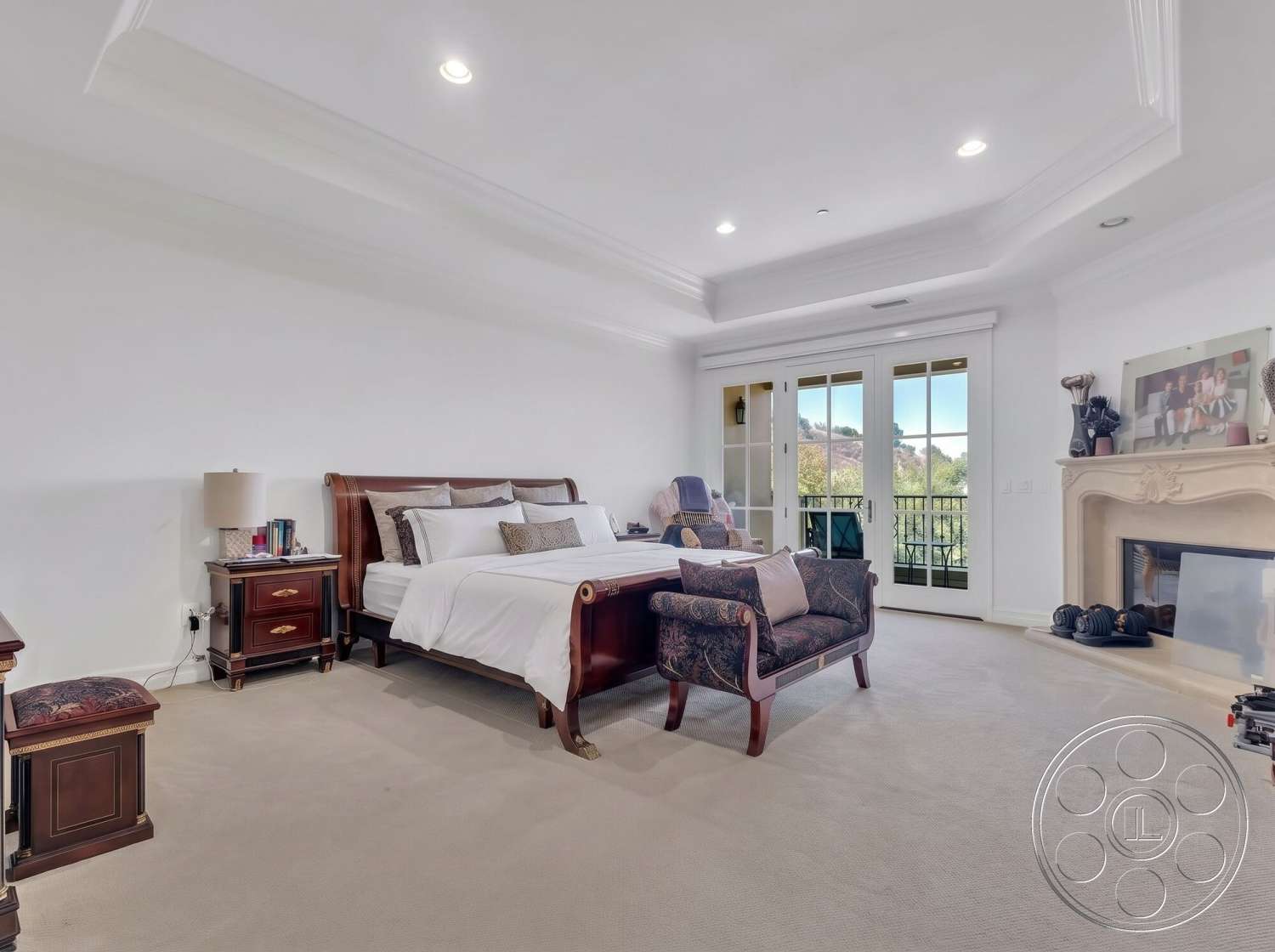 Medit 172 - decorative wall art, master bedroom, natural light from windows, upholstered armchair, neutral painted walls, stone fireplace surround, coffered ceiling details, carpet bedroom flooring, glass balcony doors, textured ceiling design, wood nightstand with drawer, traditional wood bed frame