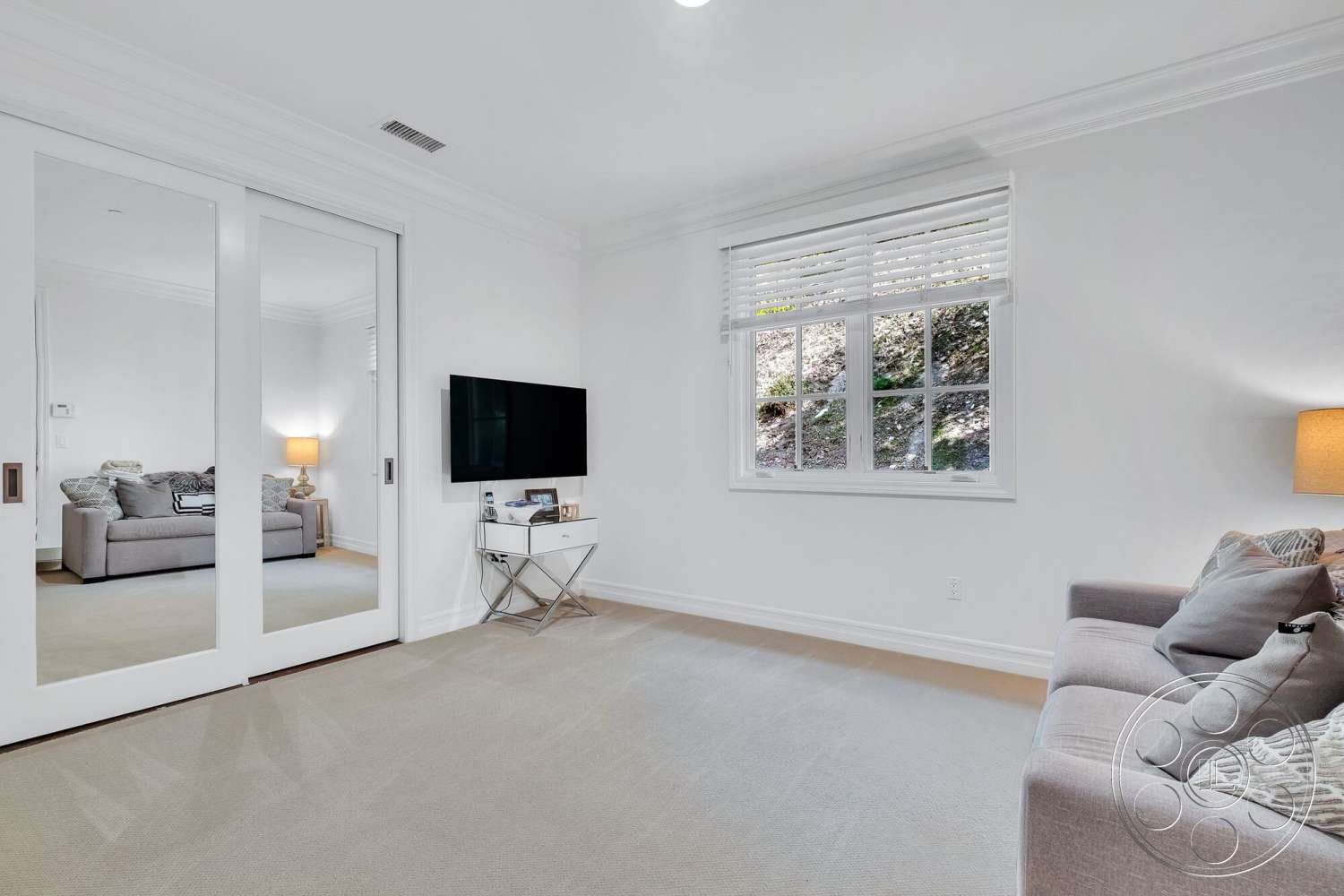 Medit 172 - floor-to-ceiling windows, gray sectional sofa, textured throw blanket, stylish throw pillows, white painted walls, crown molding details, modern wall-mounted television, minimalist side table, carpet living room flooring, paneled mirror sliding doors, contemporary accent lamp