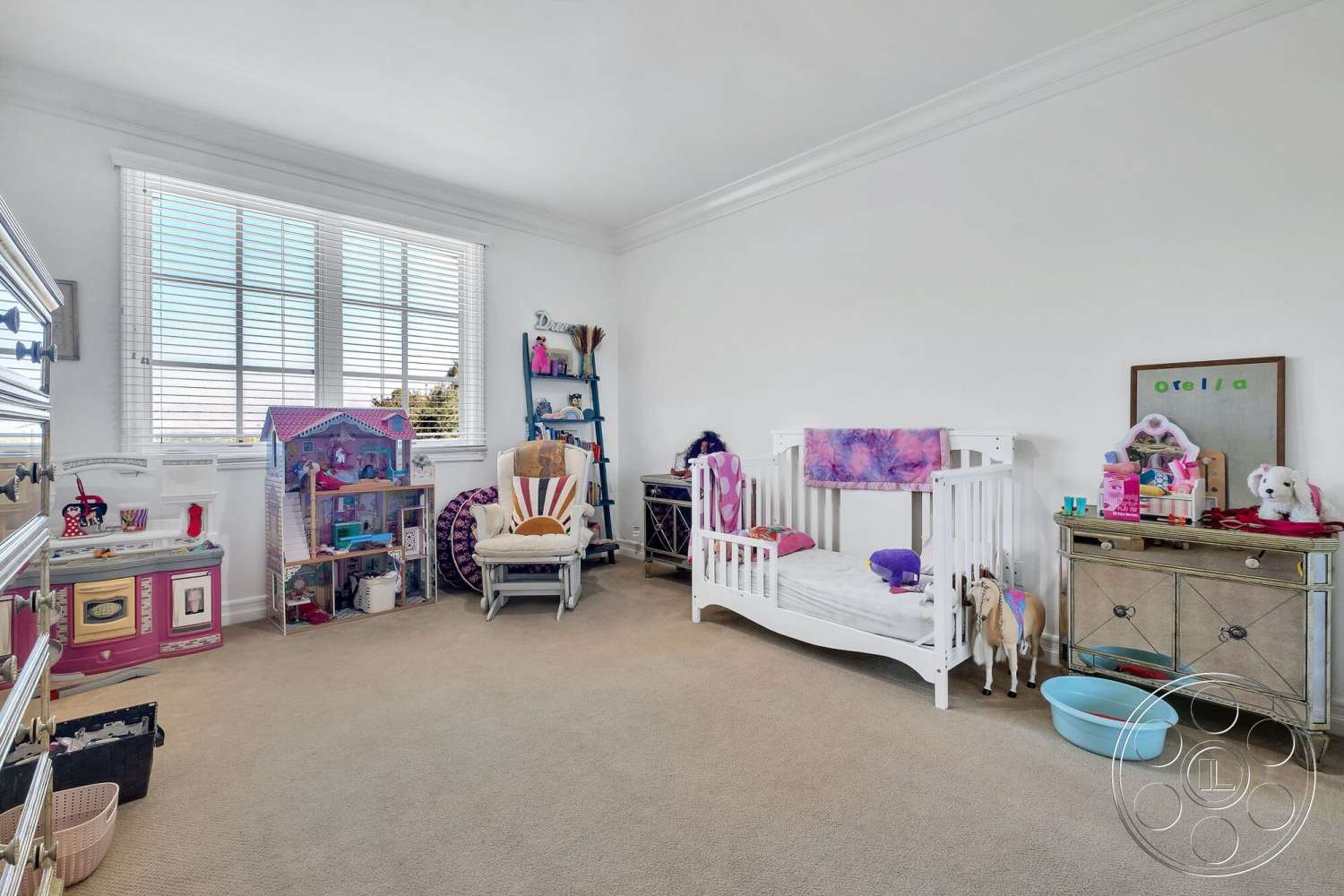 Medit 172 - white painted walls, crown molding details, carpet bedroom flooring, window with horizontal blinds, children's furniture, wooden toy storage, decorative dollhouse, gliding rocking chair, child's crib with bedding, painted wooden toy horse, mirrored dresser