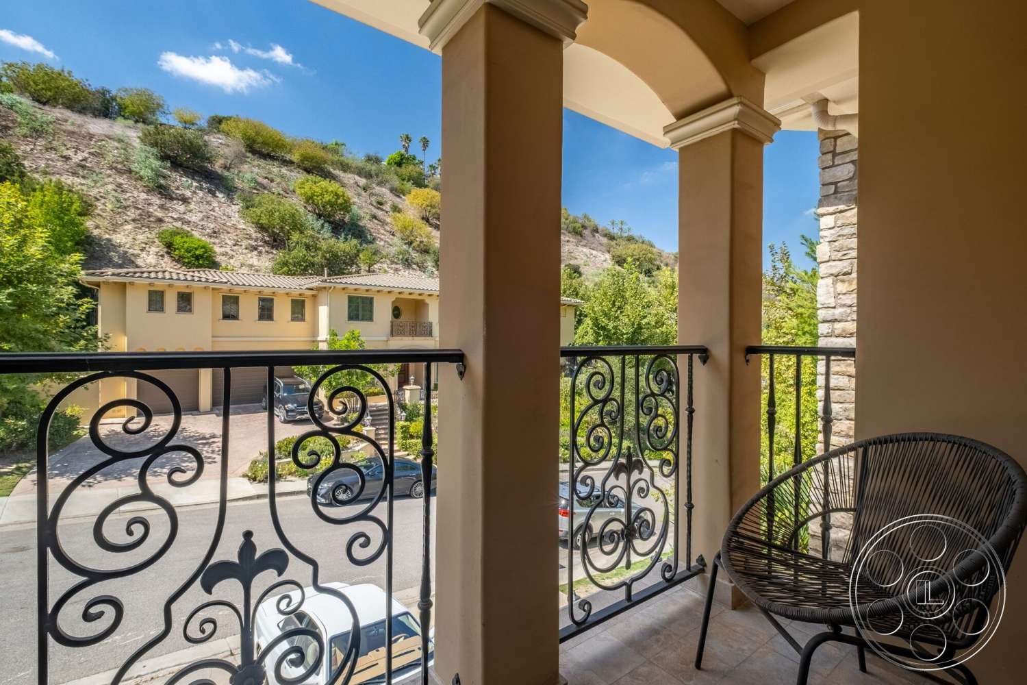 Medit 172 - textured wall finish, light-colored stucco walls, contemporary styling, urban residential setting, decorative wrought iron railing, interior balcony, stone column details, partial mountain view, surrounding green hillside, brick driveway visible