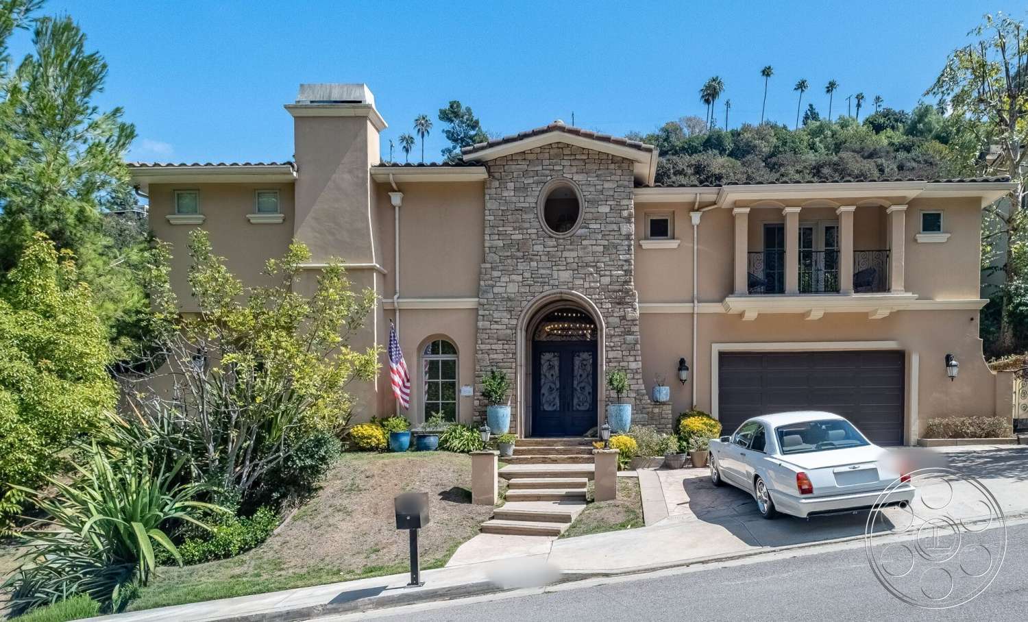 Medit 172 - exterior, concrete driveway, gabled roof, arched entryway, decorative front door, Mediterranean architectural style, two-story home, stucco wall finish, landscaped garden beds, palm tree surroundings, arched window openings, flagstone walkways, outdoor planter boxes, stone veneer accent wall, porch columns, balustrade railing details, residential front yard