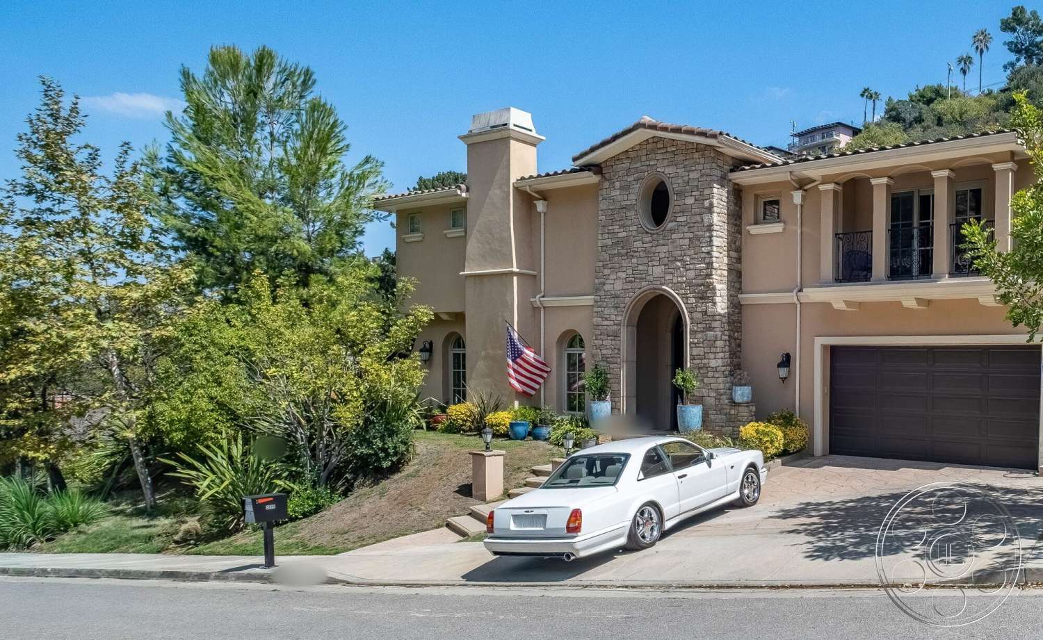 Medit 172 - exterior, landscaped front yard, paved walkway, tropical landscaping, tile roof, arched windows, two-story home, attached garage, decorative flower pots, flagstone driveway, stucco house facade, classical column details, stone archway entry, courtyard-style entrance