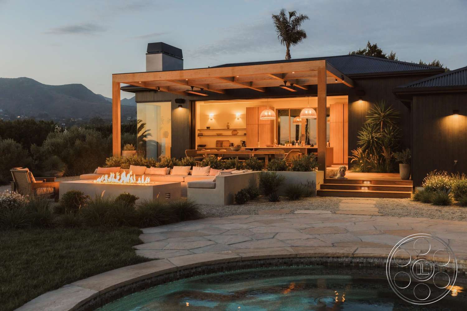 Modern 533 - exterior, landscaped garden, open floor plan, glass sliding doors, outdoor living space, modern architectural style, natural stone retaining wall, mountain view setting, concrete patio flooring, wood pergola structure, wood beam ceiling, fire pit with seating area, swimming pool with water feature, illuminated exterior