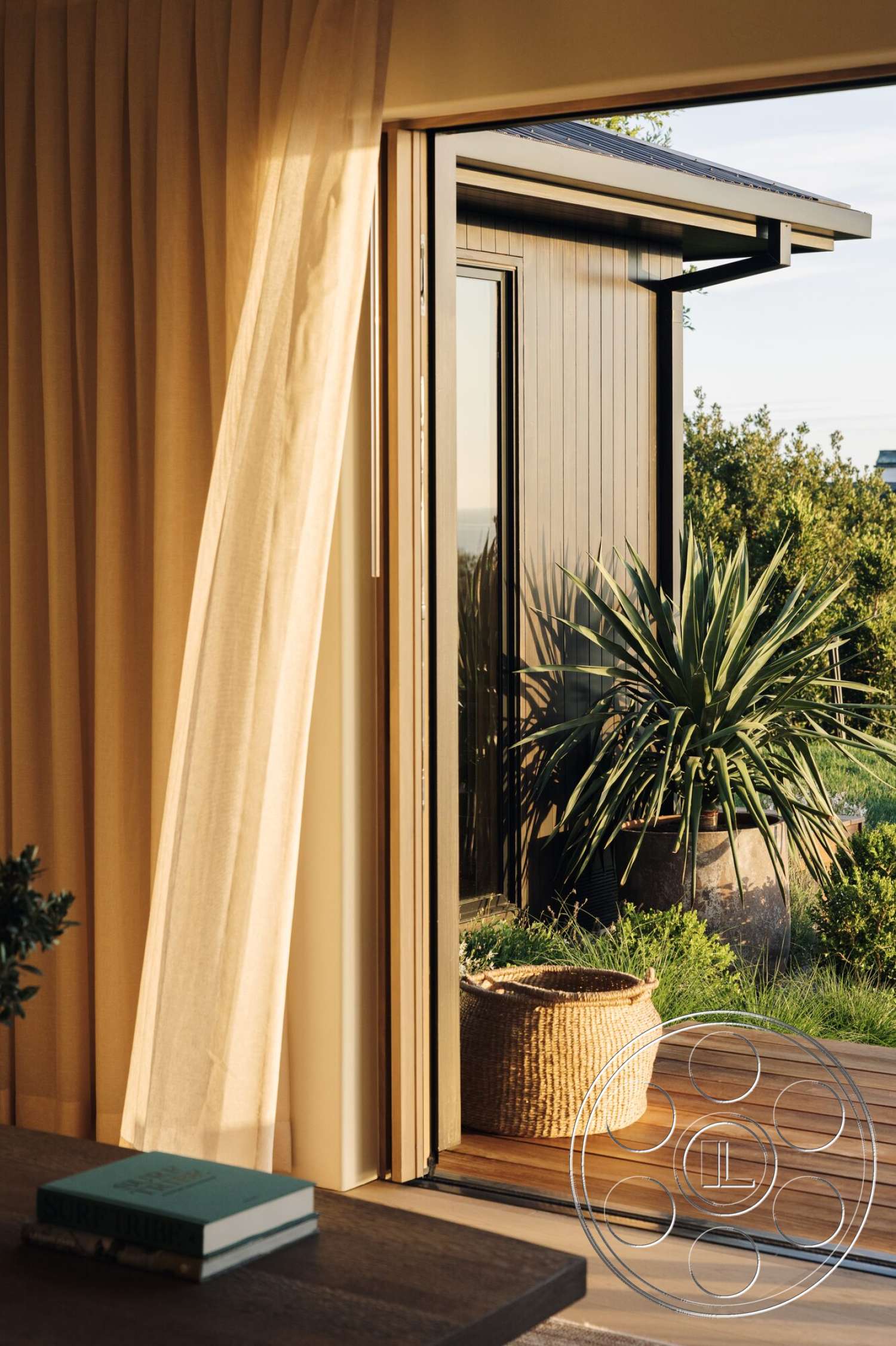 Modern 533 - curtain drapes, woven basket decor, open-concept living space, beach house, modern architectural details, wooden sliding glass doors, tall indoor plant, plant-filled outdoor area, light wood deck flooring