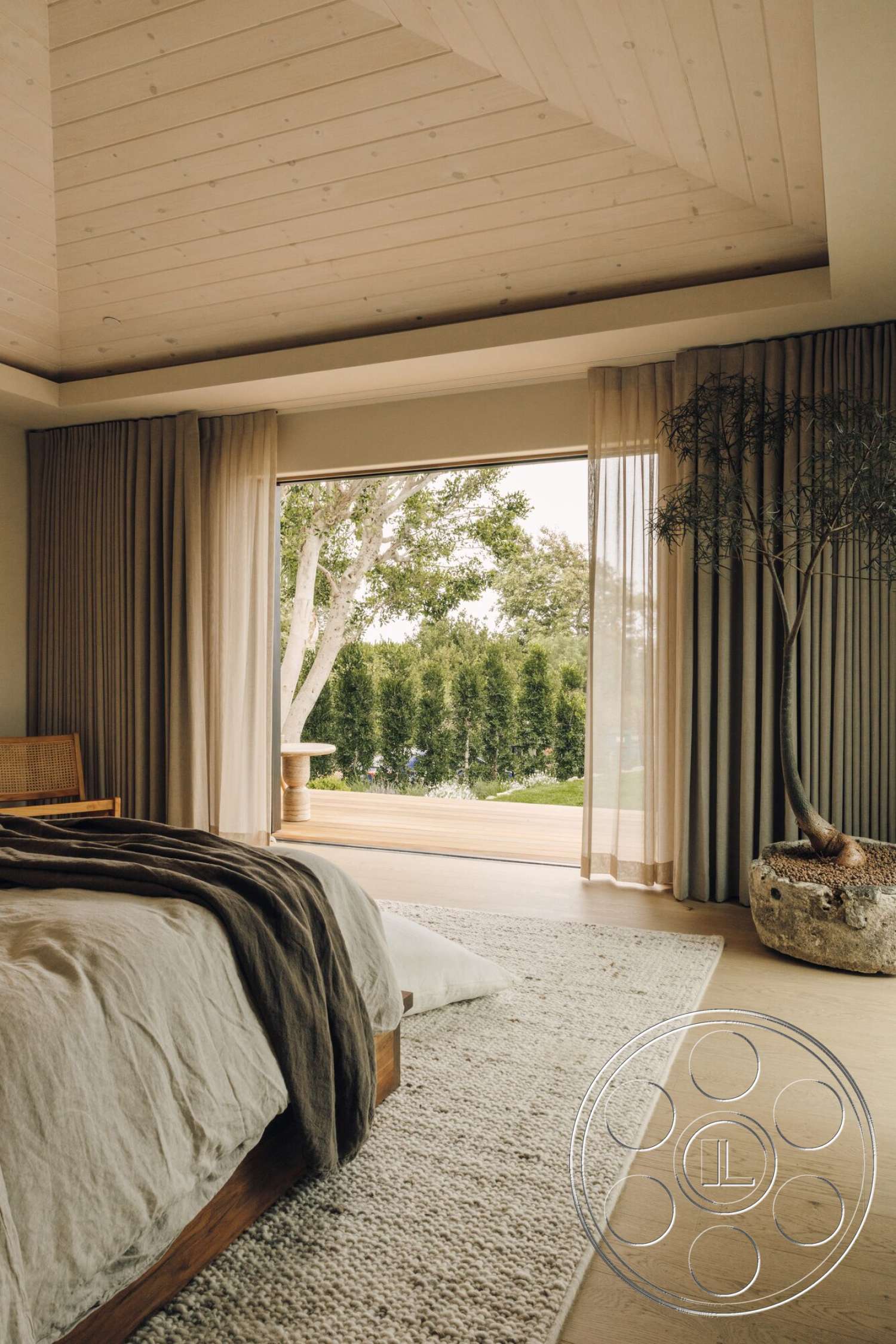 Modern 533 - large glass sliding doors, woven area rug, natural light-filled space, hardwood bedroom floors, white painted walls, suburban backyard view, wood plank ceiling, minimalist bedroom design, vaulted wood ceiling, sheer floor-length curtains, decorative potted tree