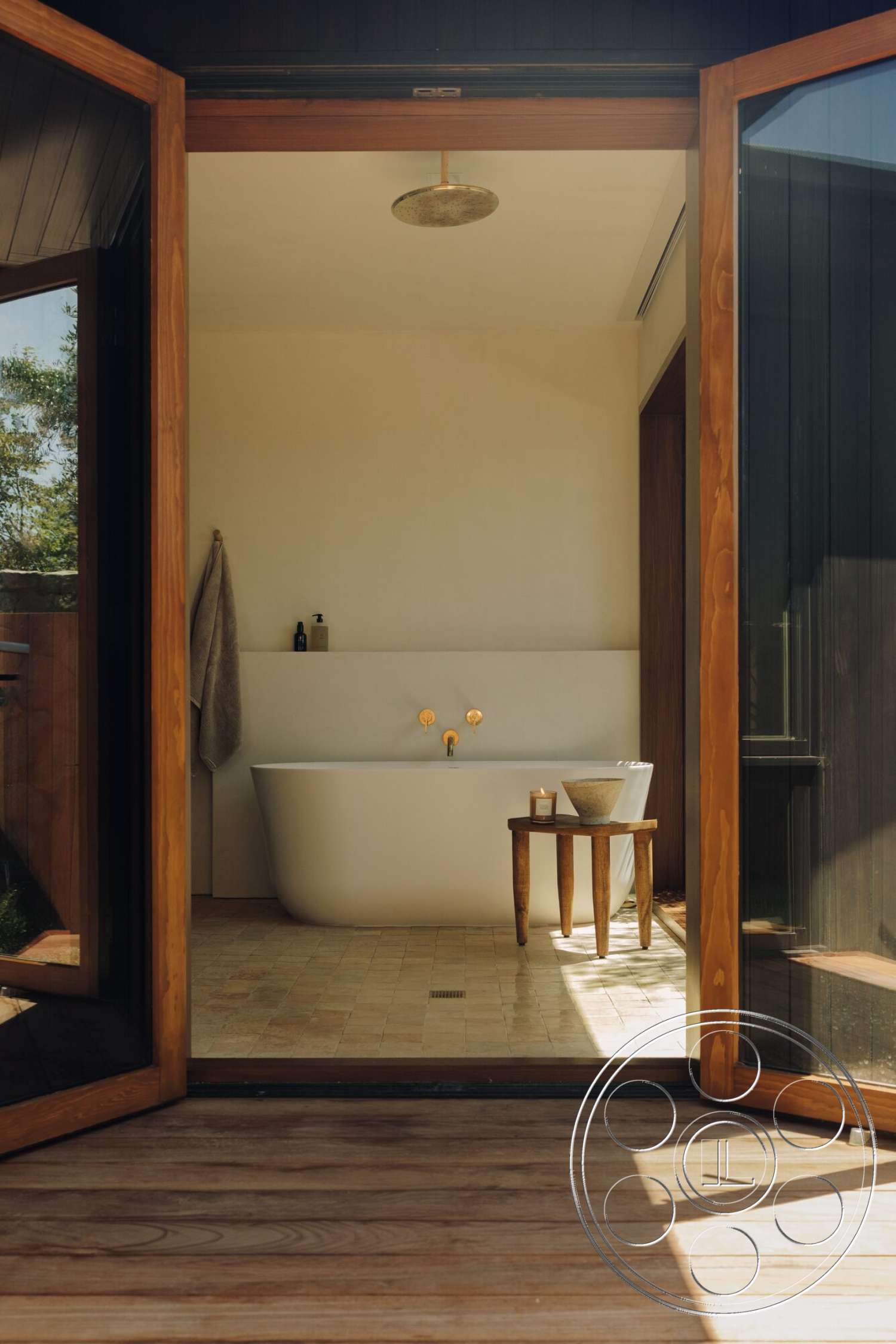 Modern 533 - exterior, freestanding bathtub, wooden side table, natural light flooding, modern minimalist design, neutral painted walls, tile bathroom flooring, golden faucet fixtures, glass door opening, wooden patio decking, textured shower ceiling, towel hanging, contemporary bathroom setting