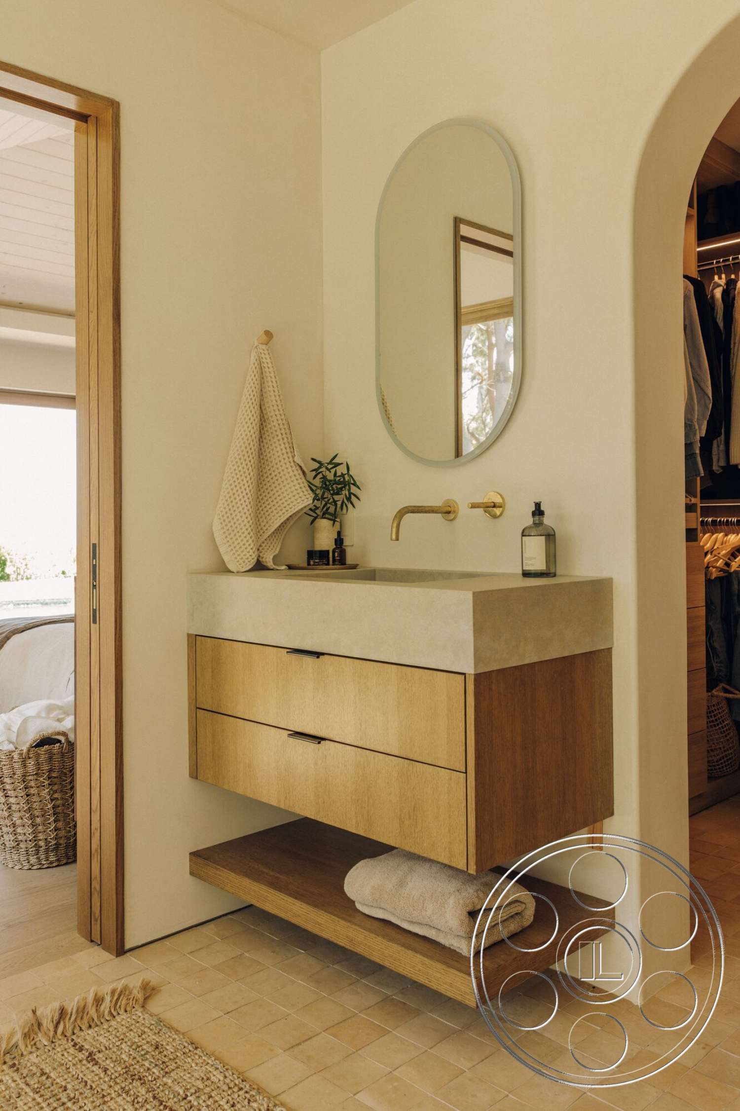 Modern 533 - oval mirror, arched doorways, textured plaster walls, natural fiber rug, light-colored tile flooring, concrete sink countertop, built-in wooden shelving, brushed gold faucet fixtures, wood floating vanity cabinet