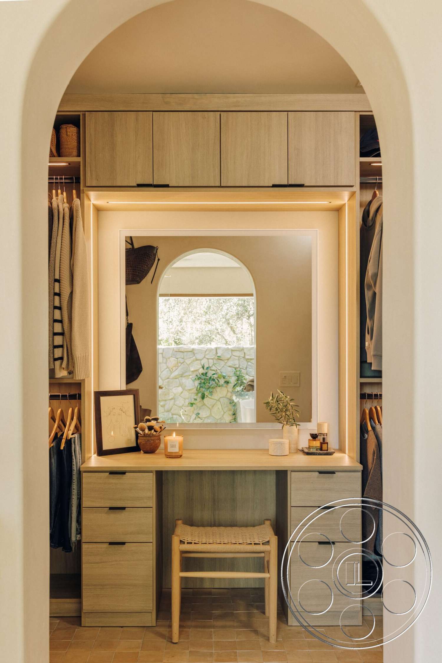 Modern 533 - neutral color palette, open shelving, light wood cabinetry, woven storage baskets, arched entryway, textured tile flooring, wooden chair with natural finish, mirrored vanity with LED lighting, natural stone wall view