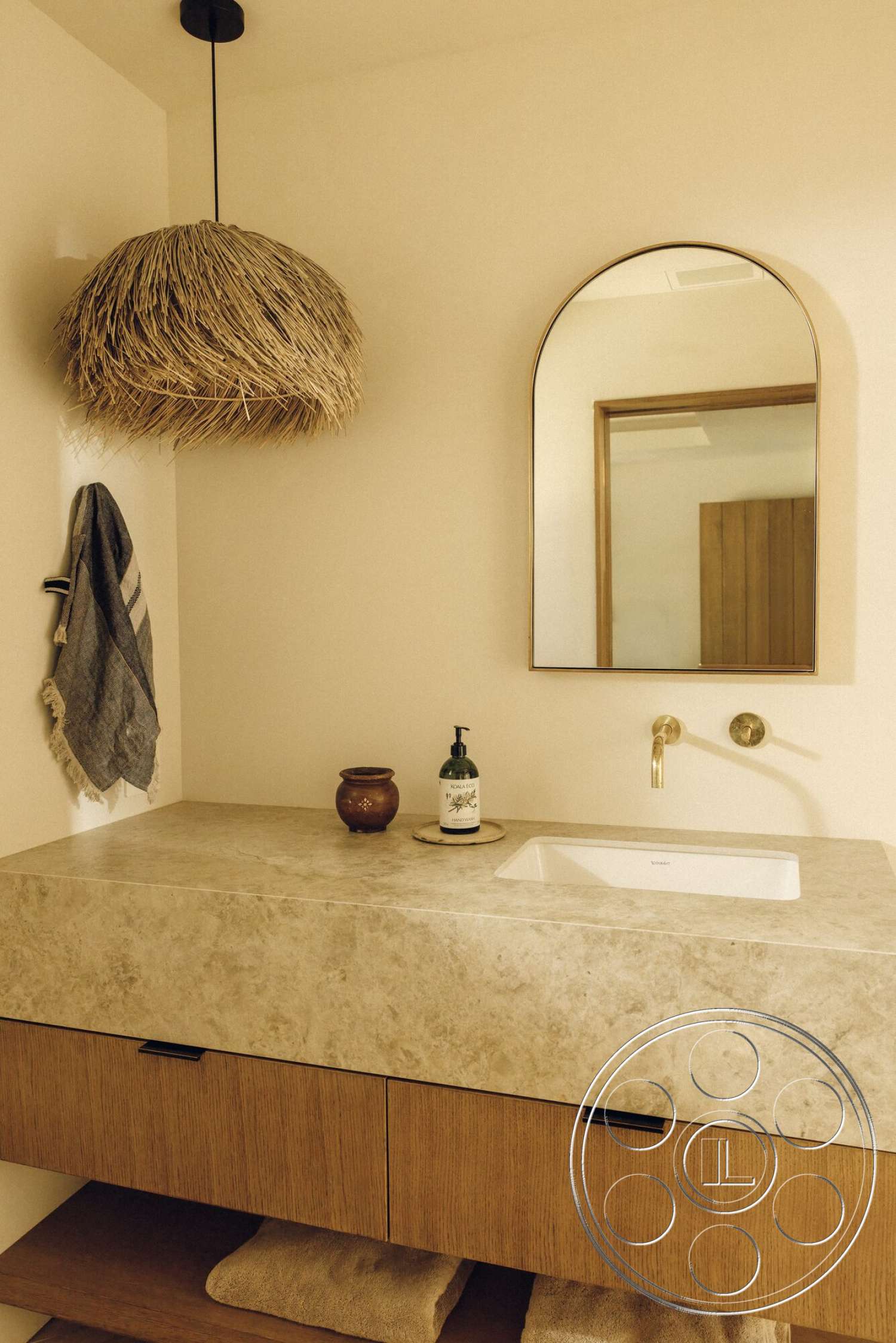Modern 533 - neutral color palette, natural light, minimalist design, textured plaster walls, pendant light fixture, soft textile accents, arched mirror, wooden bathroom cabinetry, stone vanity countertop, woven light shade, sink with modern faucet, decorative ceramic vessel, hand towel hanger