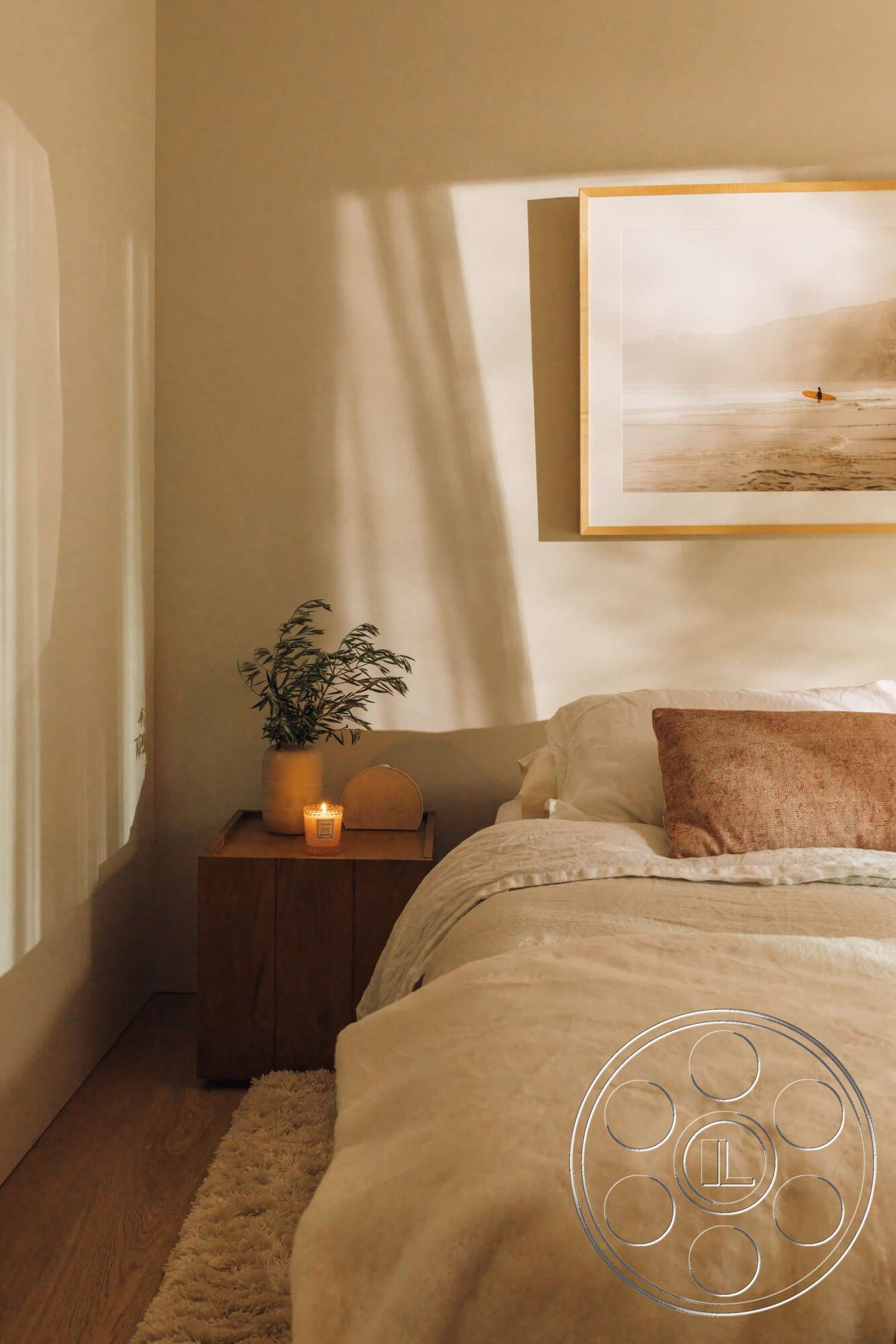 Modern 533 - decorative plant, framed wall art, soft bedding, plush area rug, textured throw pillow, warm painted walls, wood bedroom floors, nightstand with natural wood finish, lit candle accent
