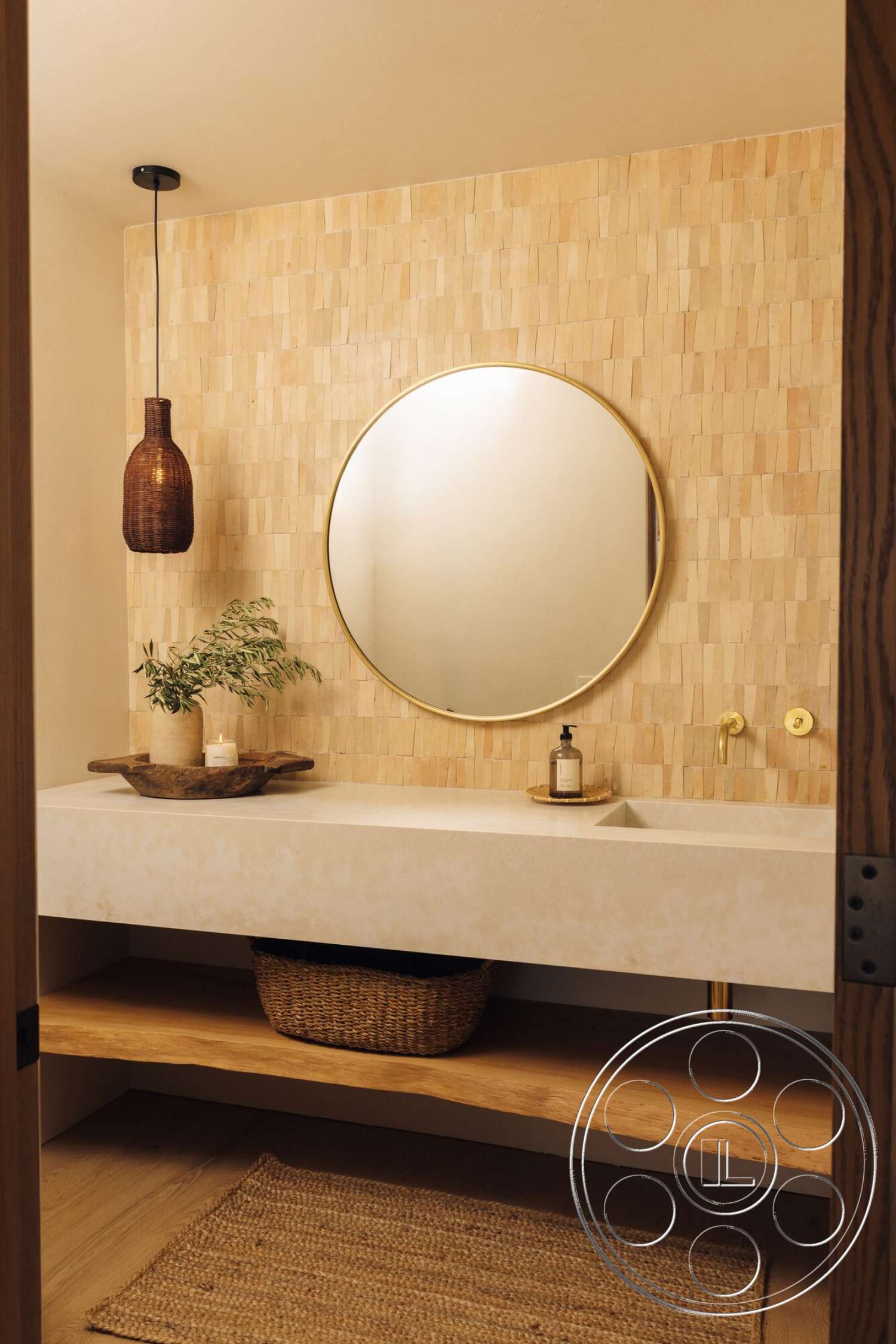Modern 533 - round mirror, pendant light fixture, gold faucet fixtures, minimalist bathroom design, textured wood wall paneling, natural wood open shelving, jute area rug, floating vanity sink, wicker storage basket