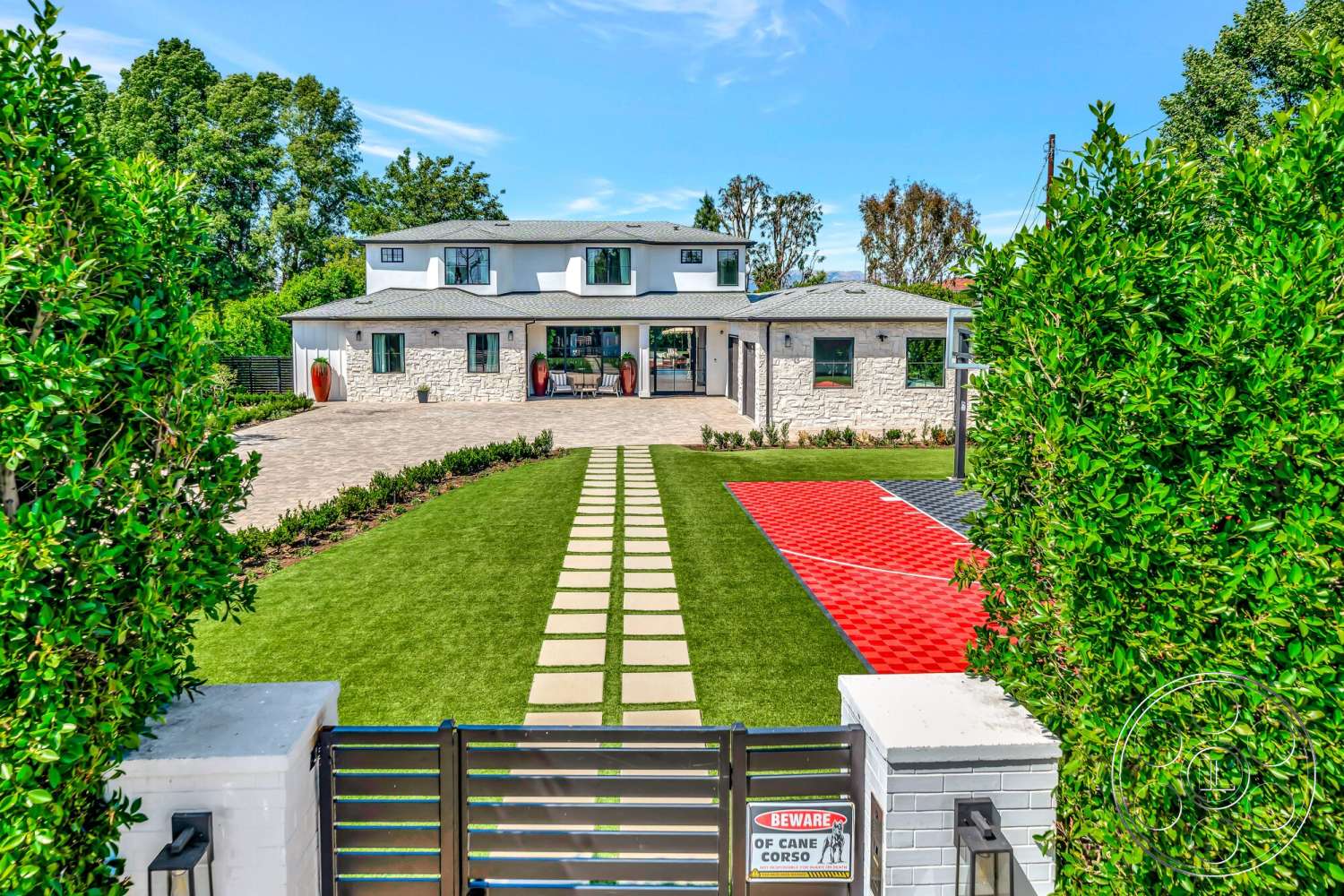 Modern 534 - exterior, asphalt shingle roof, concrete pathway, covered porch, green hedges, wooden gate, landscaped garden beds, modern farmhouse design, rectangular driveway, artificial grass lawn, large front windows, stone facade walls, red and black patterned driveway