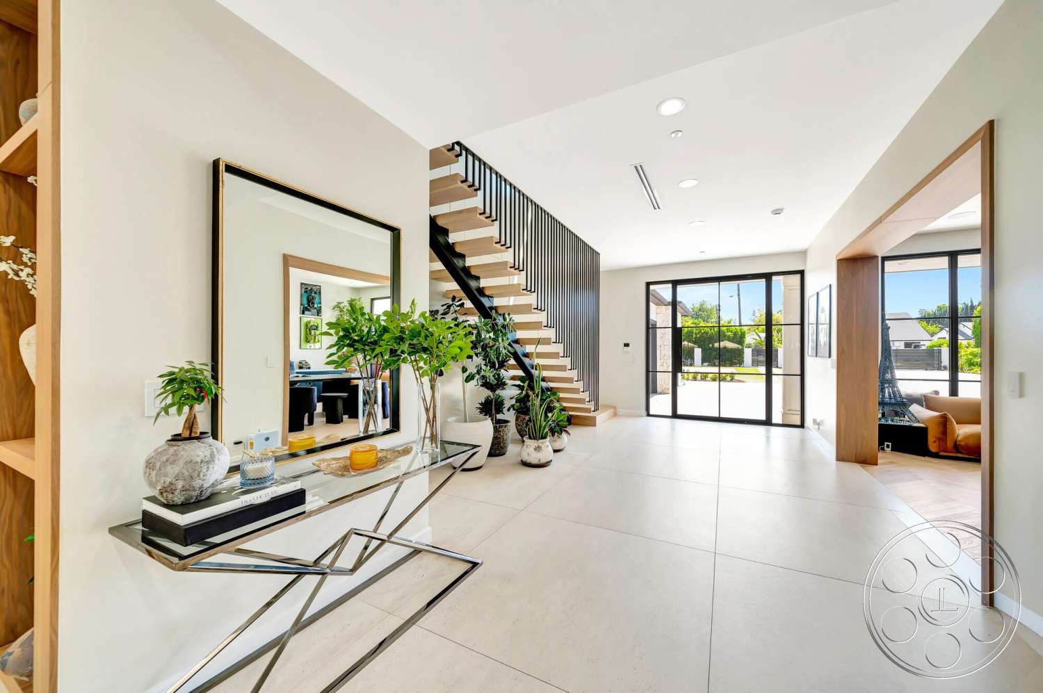 Modern 534 - natural light, minimalist design, neutral wall colors, wooden console table, open layout, decorative vases, green indoor plants, framed mirror, large floor-to-ceiling windows, wooden stair treads, light-colored tile flooring, metal stair railings, contemporary entryway