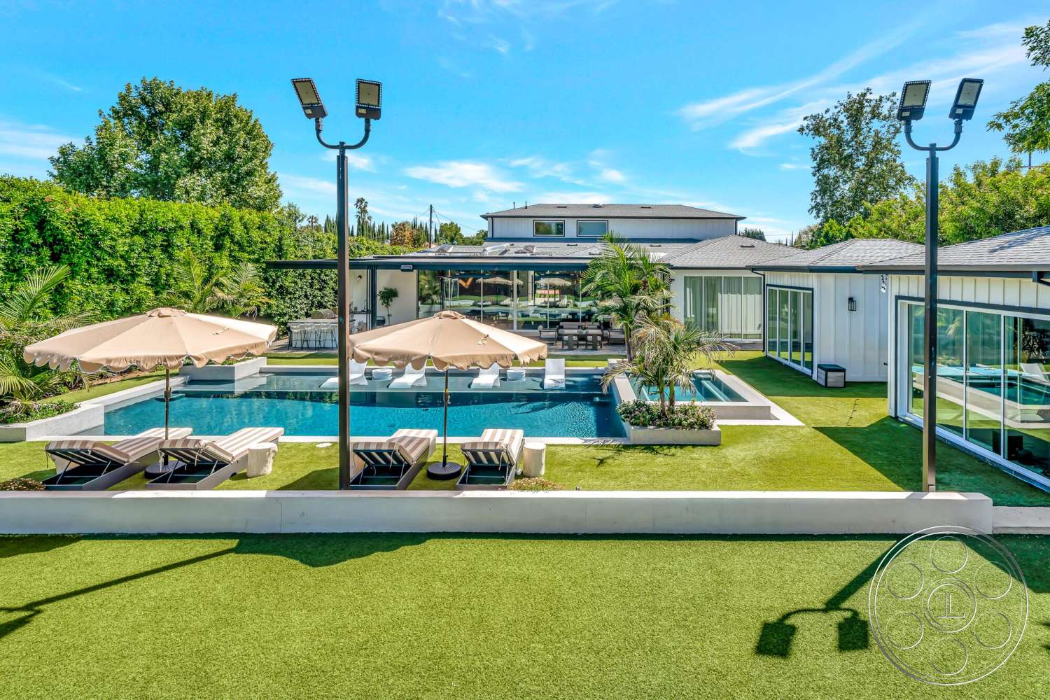Modern 534 - exterior, large glass windows, paved walkway, outdoor lounge area, patio seating, potted greenery, modern architectural style, poolside lounge chairs, rectangular pool, surrounding landscape, stone pool deck, flat roof design, concrete pool border, synthetic grass lawn, metal patio umbrellas