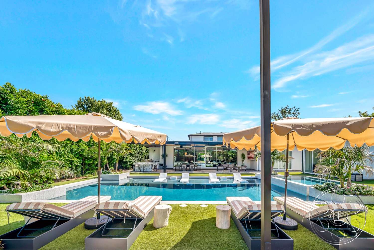 Modern 534 - exterior, landscaped garden, modern architecture, glass sliding doors, outdoor lounge area, infinity pool, natural stone wall, concrete pool deck, two-story house, stone planters, urban backyard, synthetic grass lawn, canvas umbrellas, striped outdoor lounge chairs