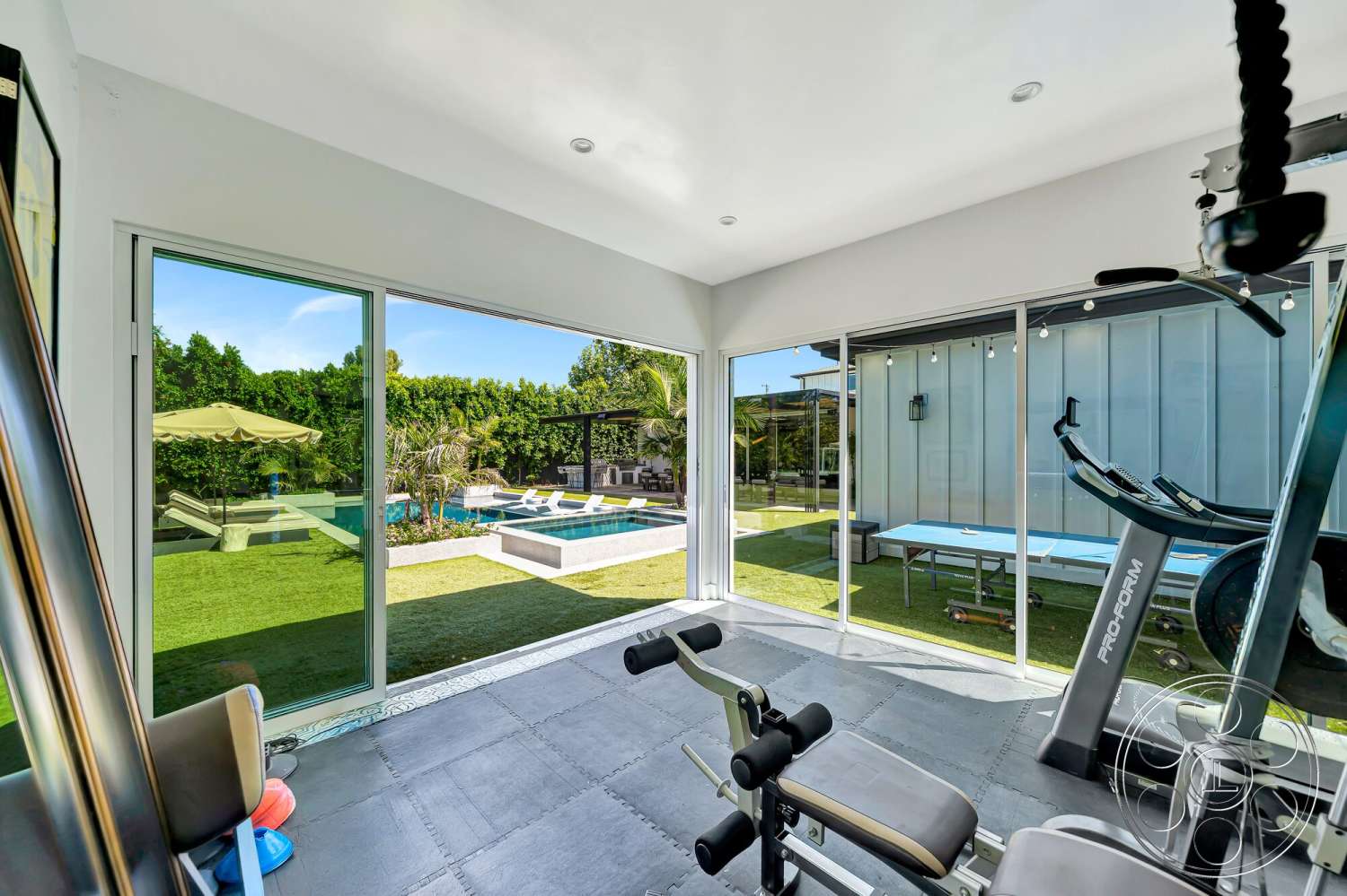 Modern 534 - landscaped garden, rubber flooring, glass sliding doors, rectangular swimming pool, outdoor lounge area, natural light from large windows, concrete pool deck, modern fitness equipment, interior gym space, lush green backyard setting