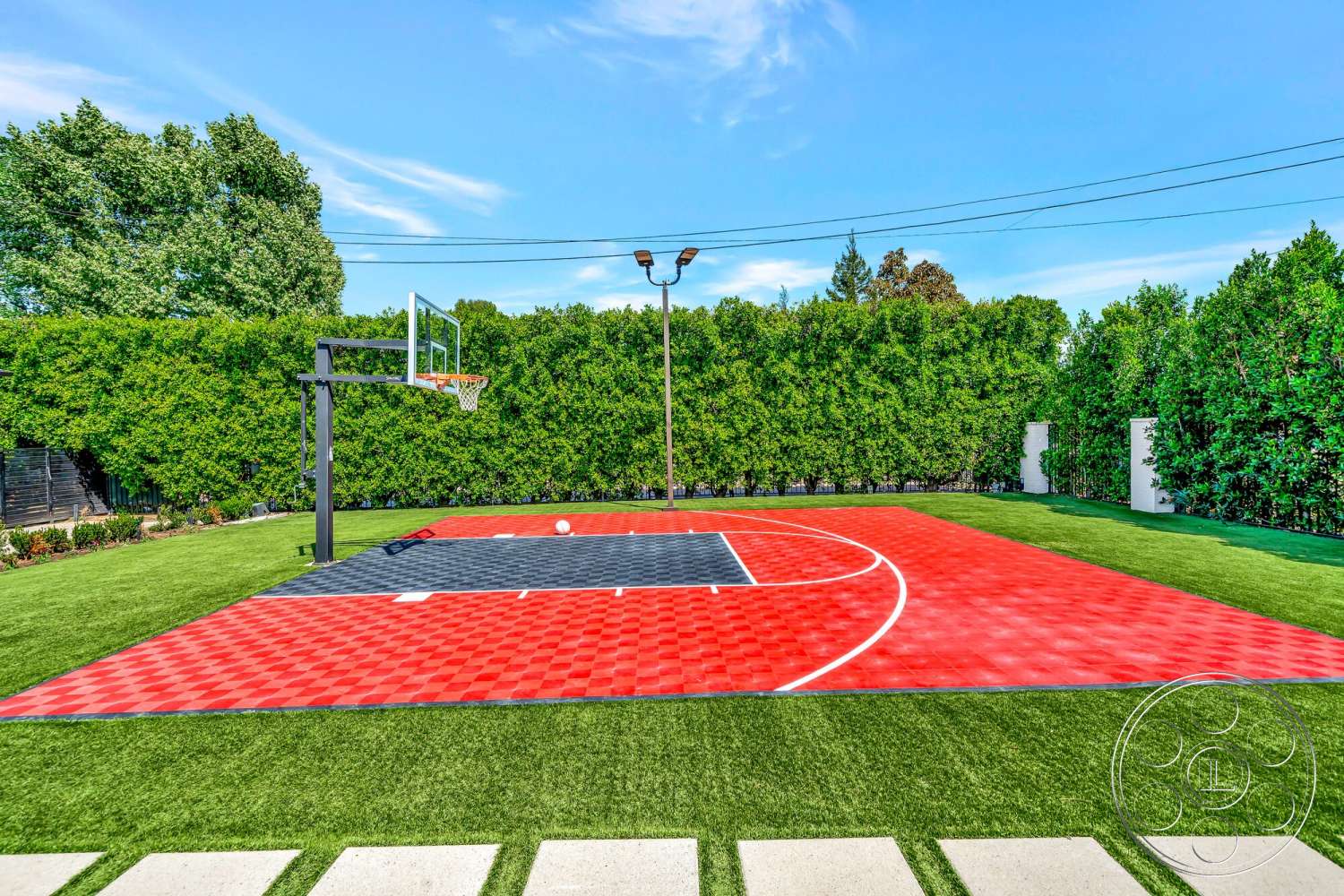 Modern 534 - exterior, outdoor sports area, landscaped garden setting, artificial grass lawn, paved concrete pathway, red and black patterned basketball court, basketball hoop with black metal support, green hedge privacy fence, curved freeform court layout