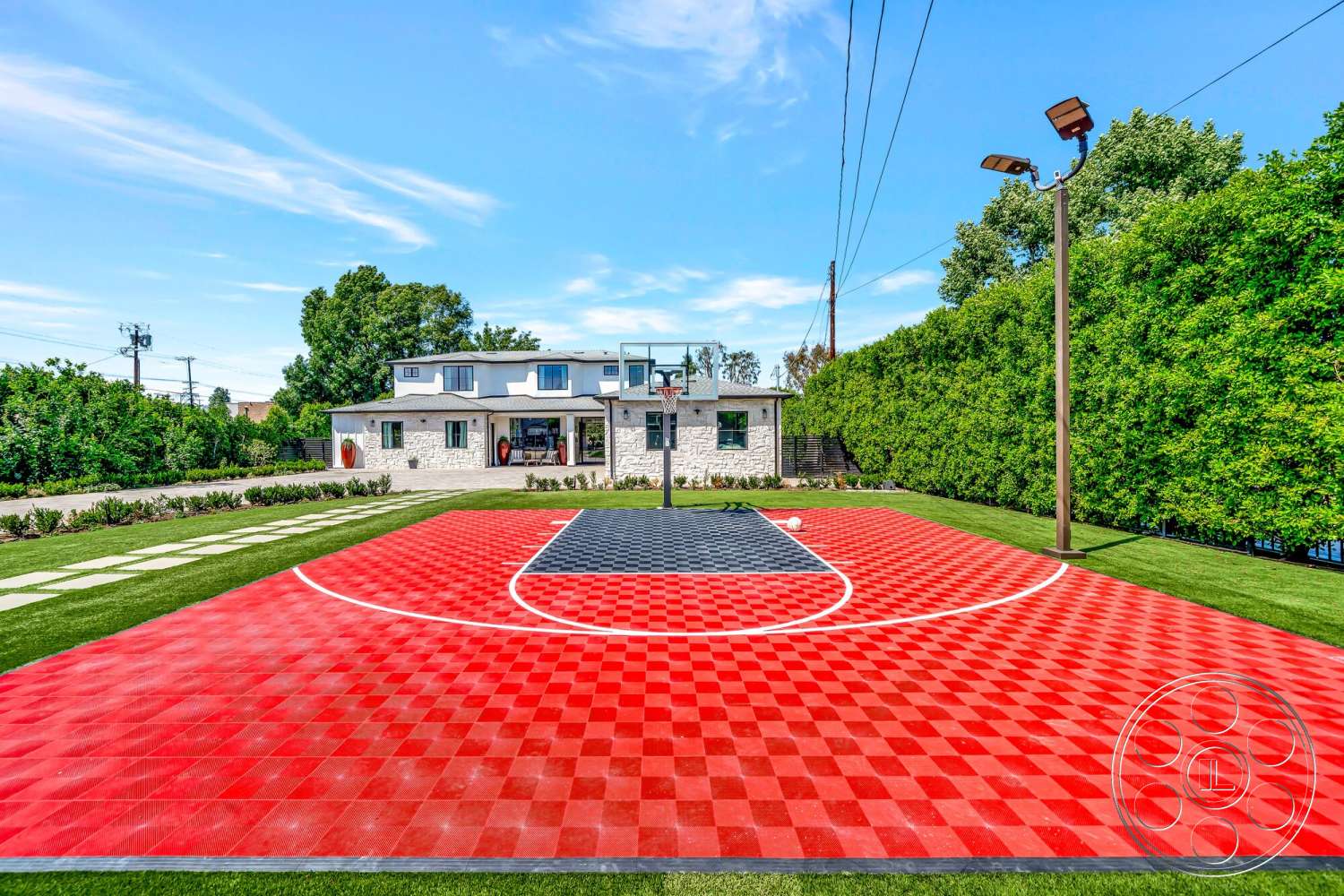 Modern 534 - exterior, tall hedges, hardscaped pathway, outdoor lighting fixtures, two-story home, landscaped garden beds, red basketball court surface, black basketball court surface, grass surrounding basketball court, stone house exterior walls