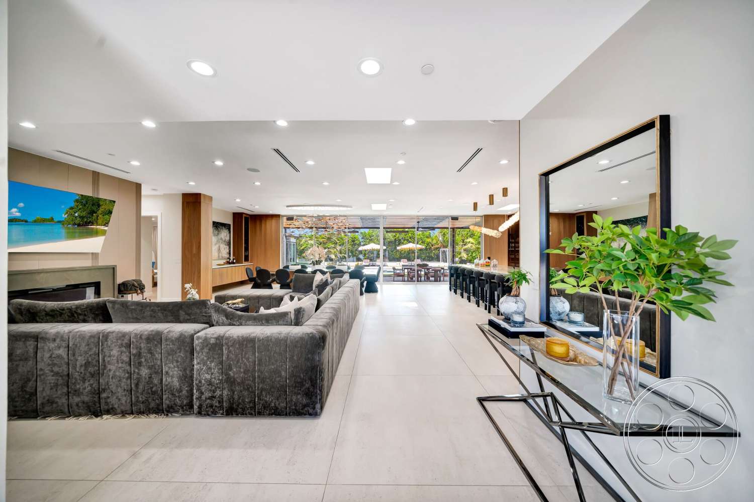 Modern 534 - indoor plants, open floor plan, decorative mirror, floor-to-ceiling windows, bright natural lighting, minimalist coffee table, contemporary chandelier, modern dining area, light-colored tile flooring, modern art display, wood kitchen cabinetry, grey upholstered sectional sofa, wood-paneled accent wall