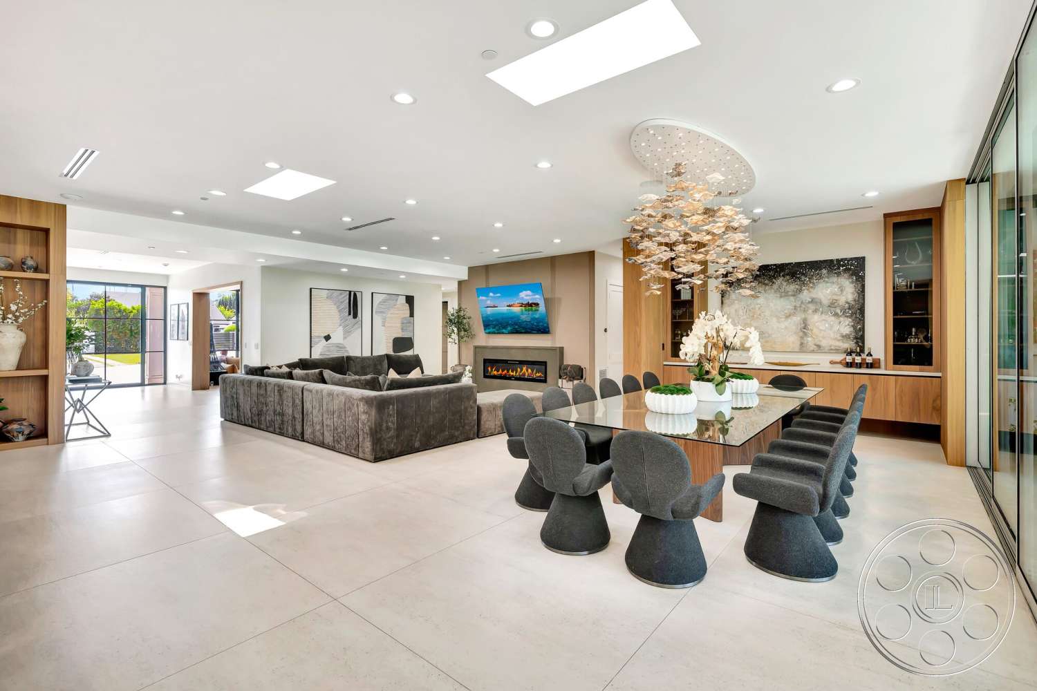 Modern 534 - neutral color palette, concrete flooring, plush sectional sofa, modern chandelier, rectangular dining table, wood accent walls, exposed wood ceiling beams, open concept living area, built-in shelving units, stone fireplace surround, artwork wall display, skylight ceiling, glass wall partition, curved dining chairs